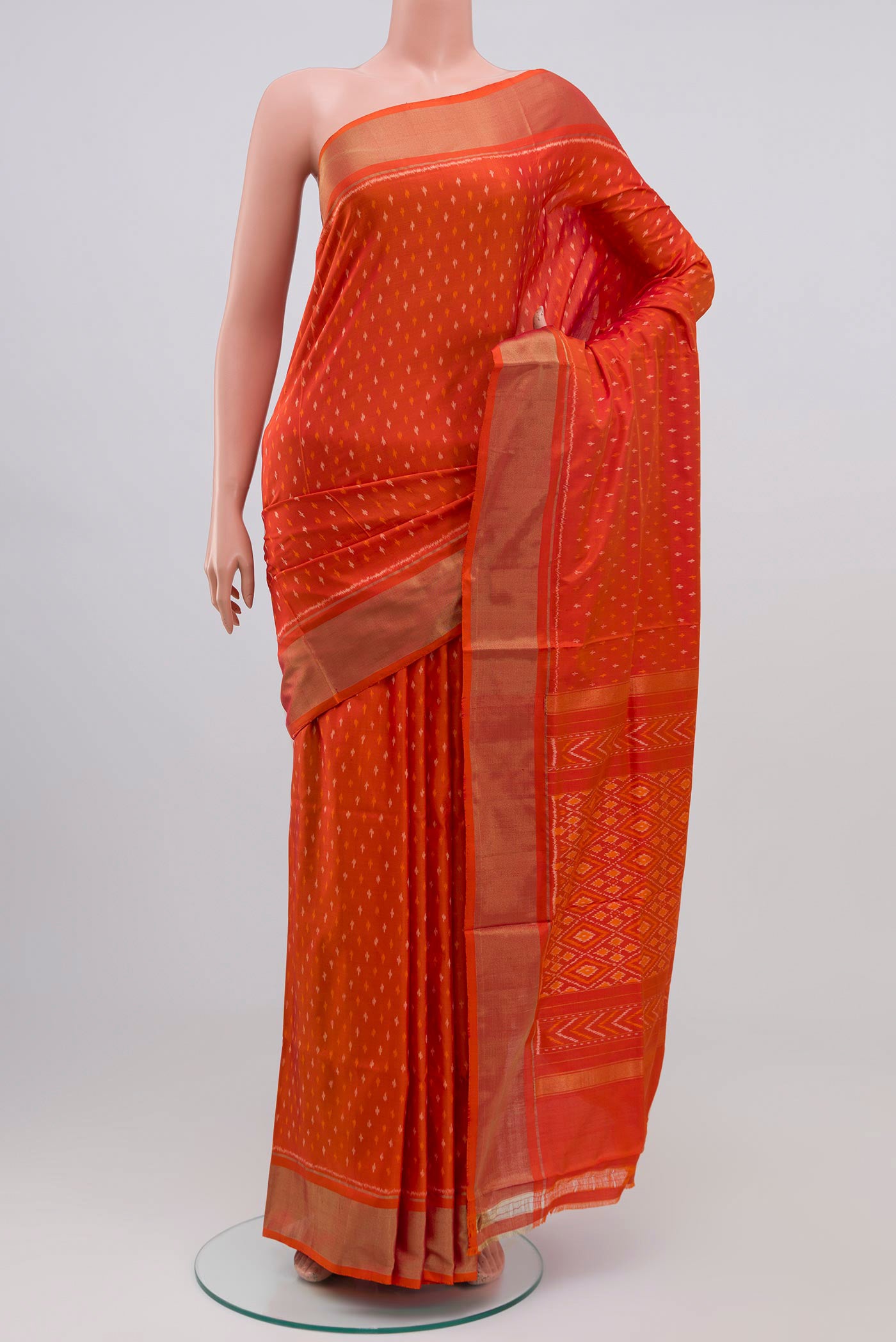 Orange Pochampally Silk Saree with Ikat design on the body and Zari Border.  displayed on a mannequin