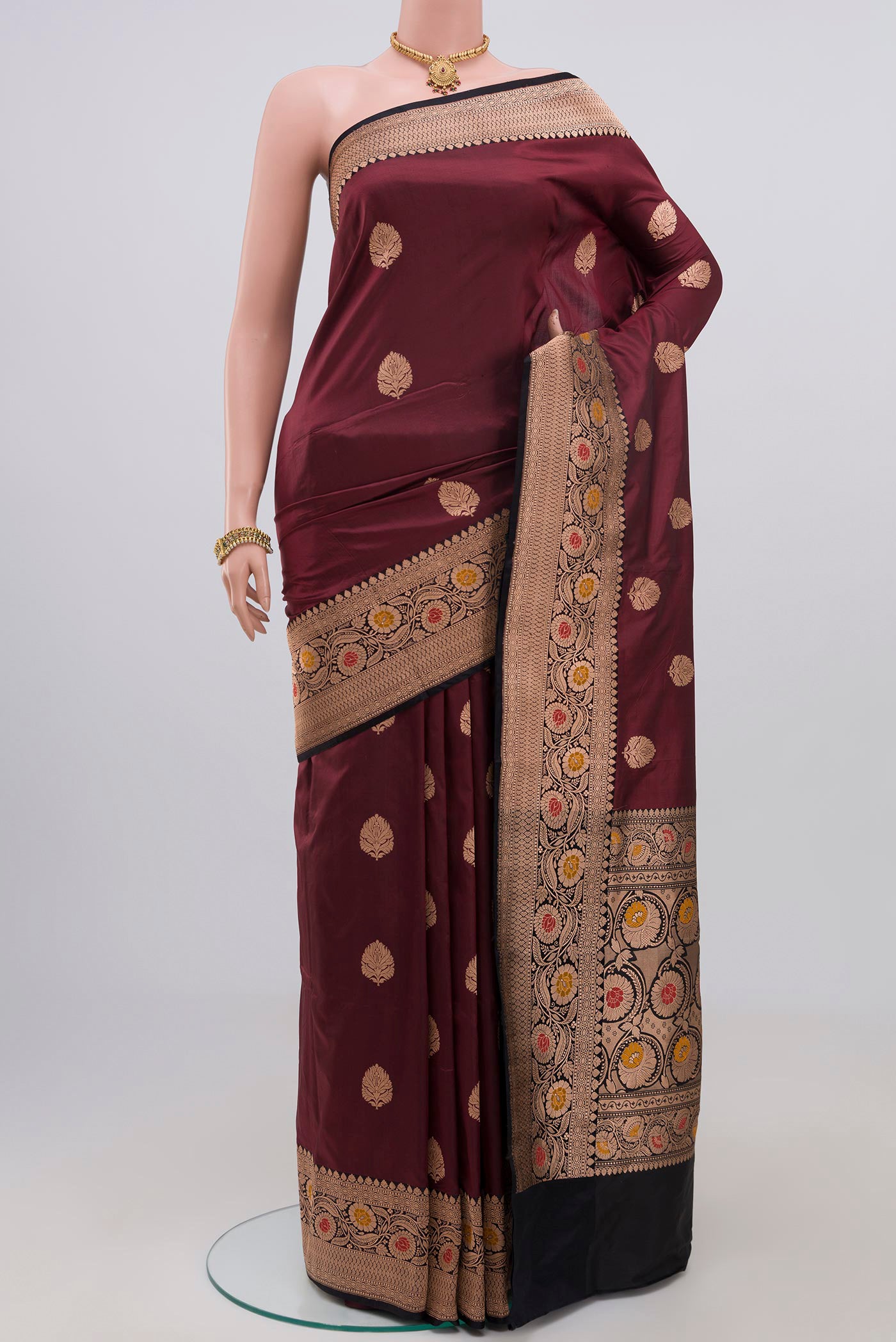 Maroon Banarasi Katan Silk Saree with Zari Butta on the body and Zari Border.  displayed on a mannequin