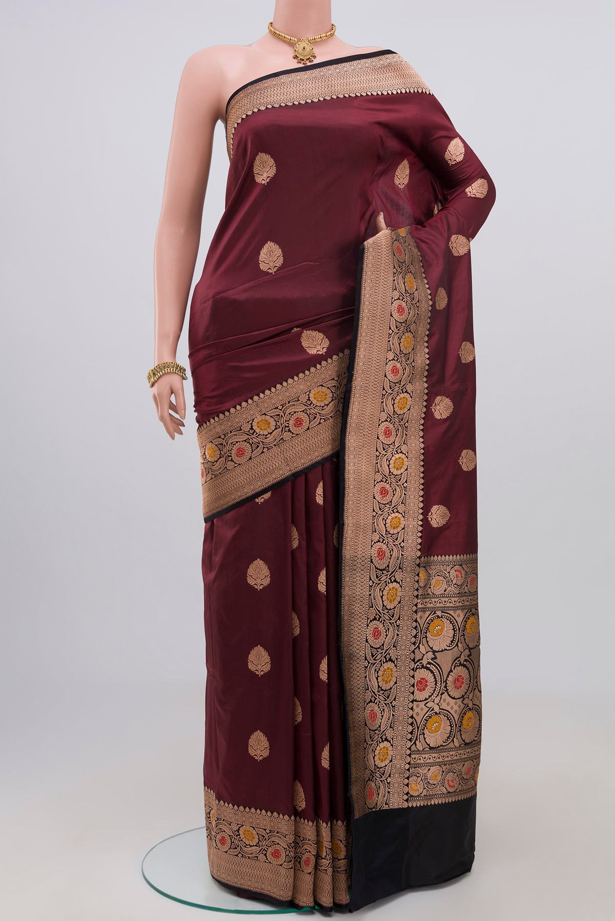 Maroon Banarasi Katan Silk Saree with Zari Butta on the body and Zari Border.  displayed on a mannequin