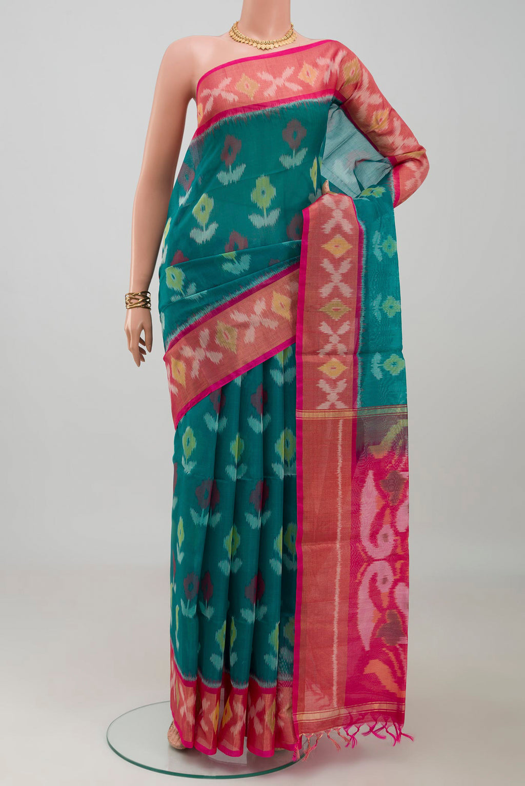 Green Silk Cotton Saree with Ikat design on the body and Zari Border.  displayed on a mannequin