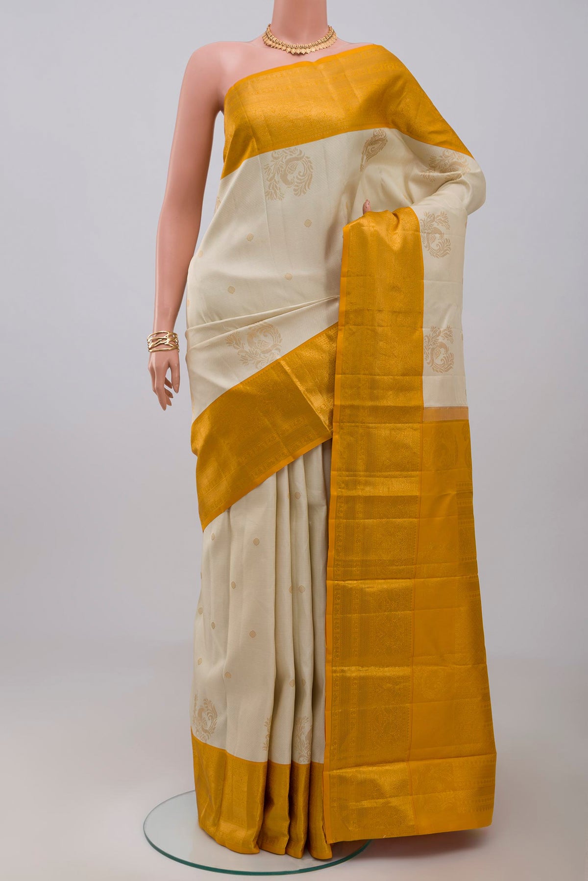 Cream Kanjivaram Saree with Zari Butta on the body and Zari Border.  displayed on a mannequin