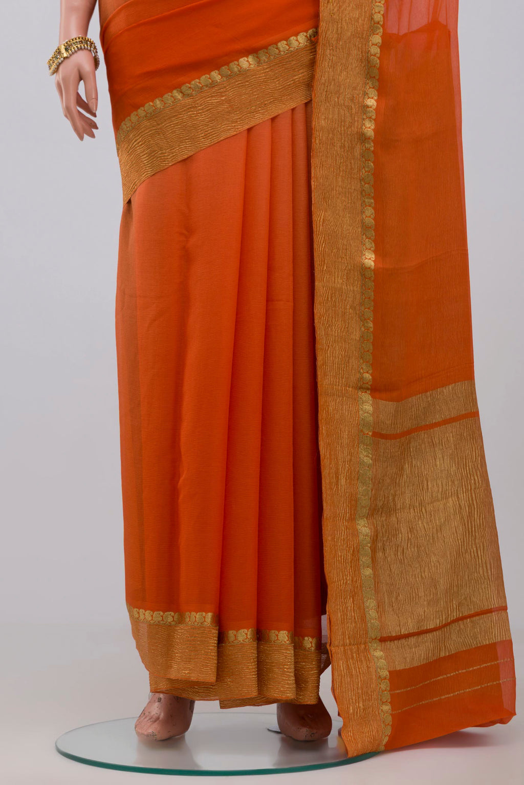 Pleats and pallu of Orange Chiffon Saree with Plain Body and Zari Border. 