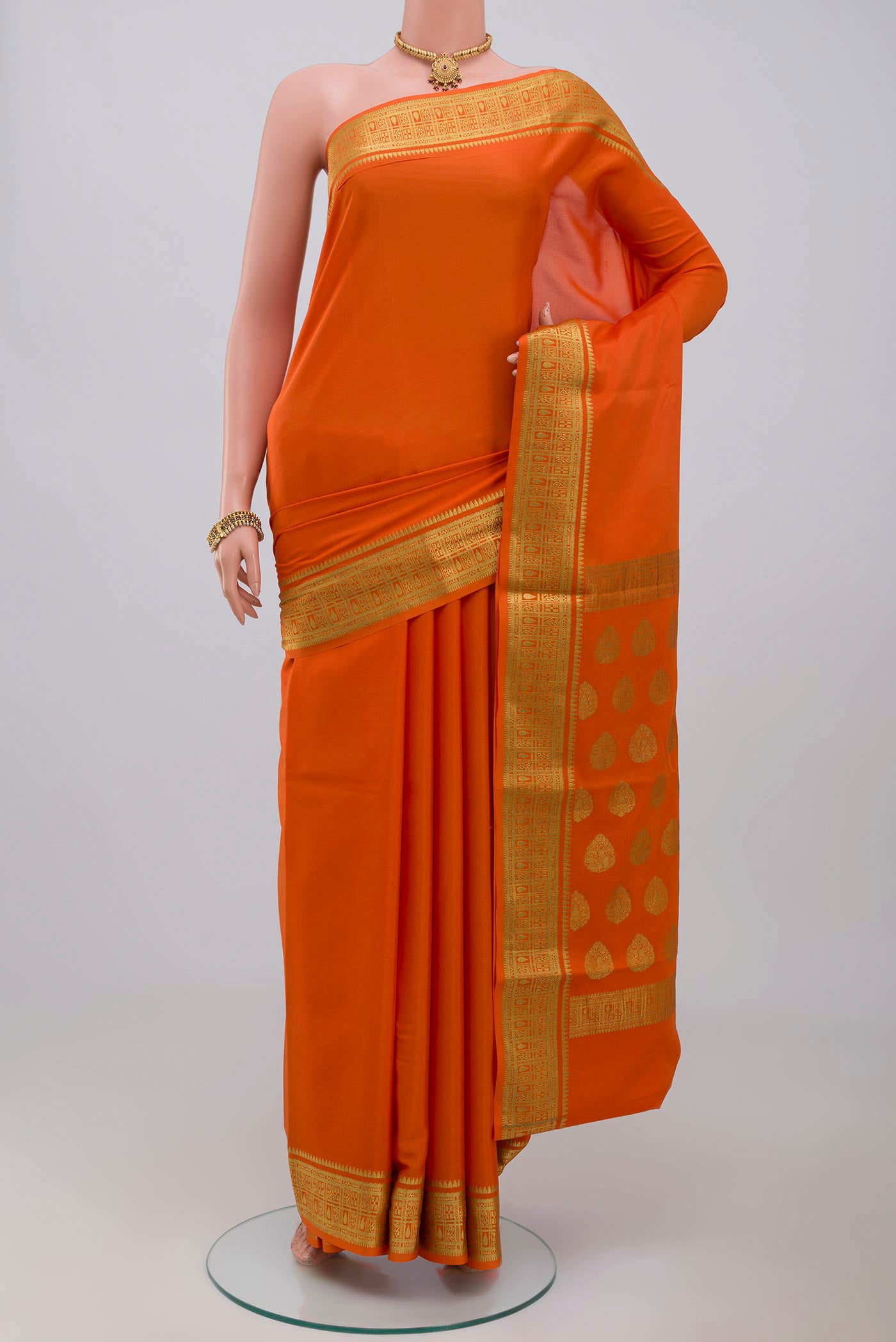 Orange Crepe Saree with Plain Body and Zari Border.  displayed on a mannequin