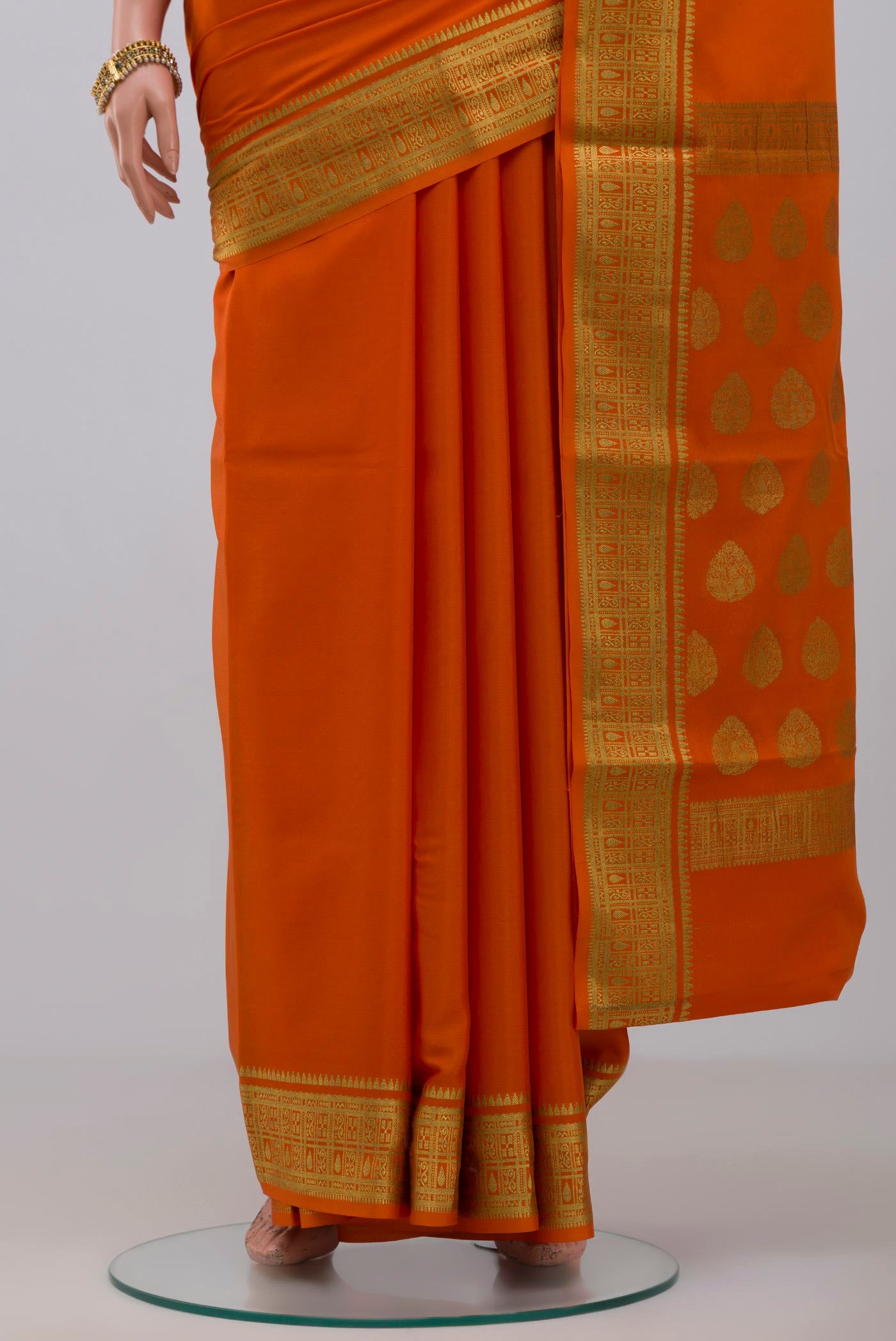 Pleats and pallu of Orange Crepe Saree with Plain Body and Zari Border. 