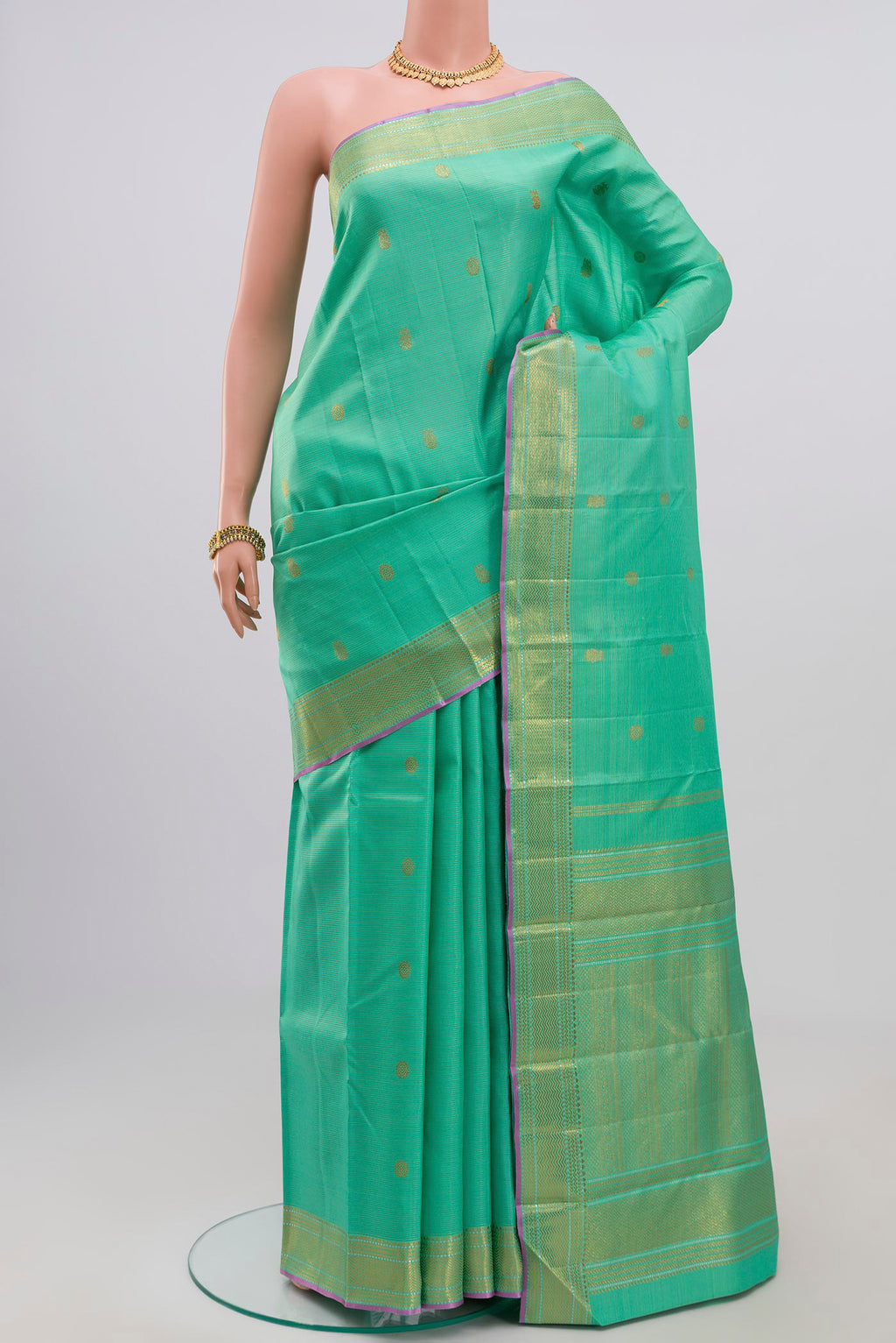 Green Kanjivaram Saree with Zari Butta on the body and Zari Border.  displayed on a mannequin