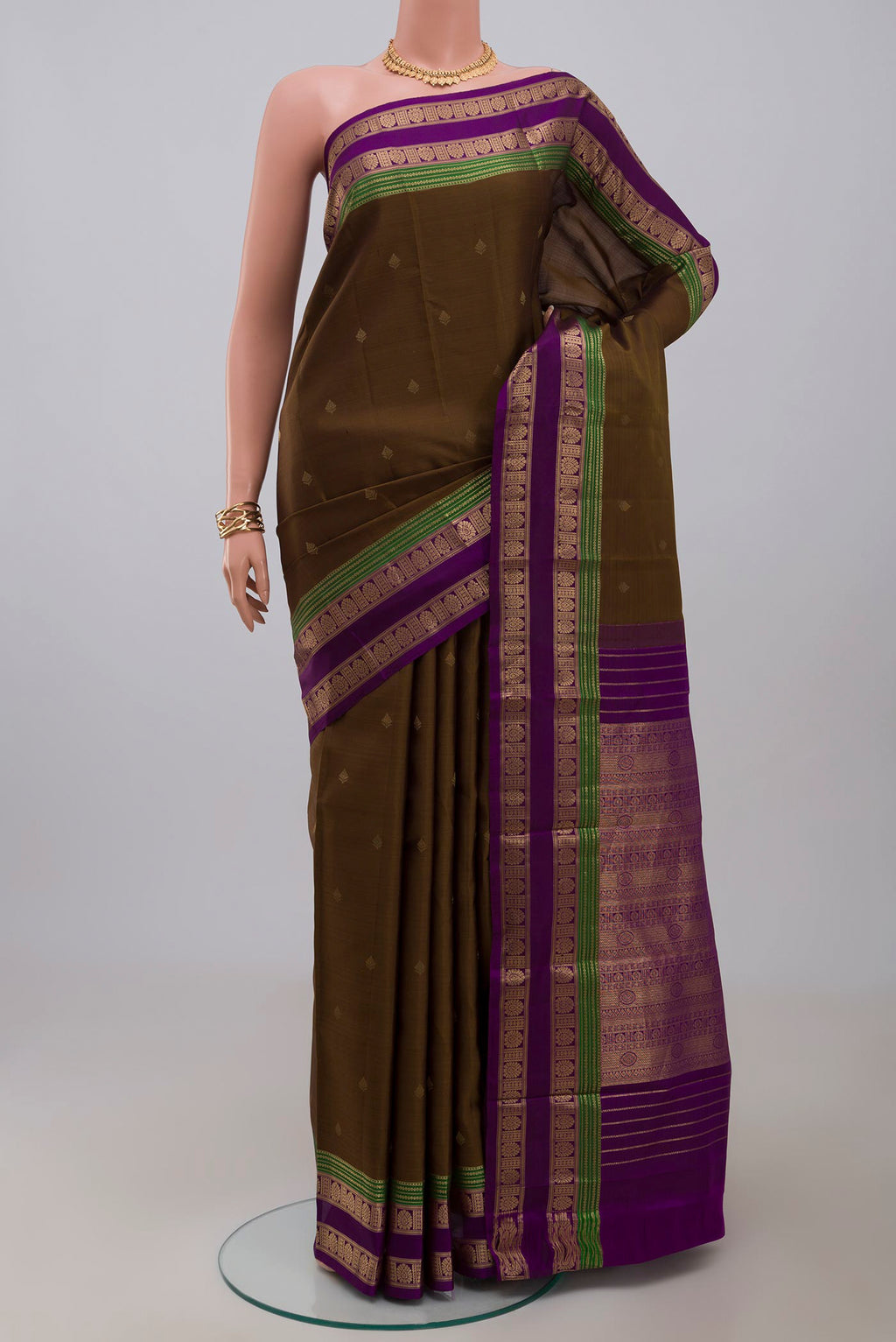Mehandi Green Kanchipuram Silk Saree with Zari Butta on the body and Zari Border.  displayed on a mannequin