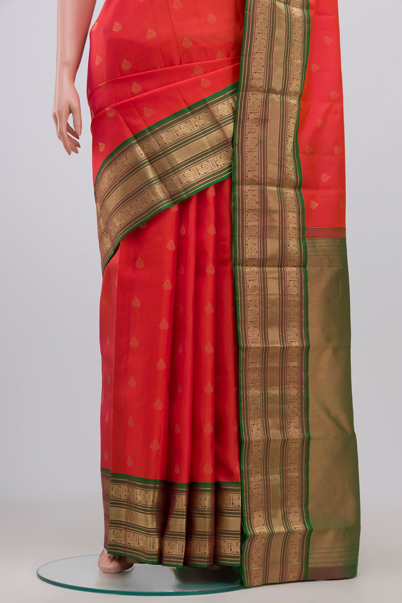 Pleats and pallu of Orange Kanchipuram Saree with Zari Butta on the body and Zari Border. 