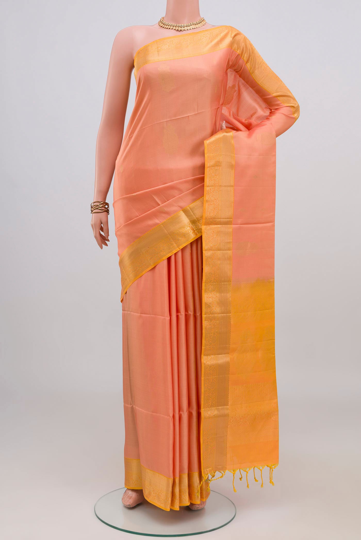 Peach Soft Silk Saree with Zari Butta on the body and Zari Border.  displayed on a mannequin