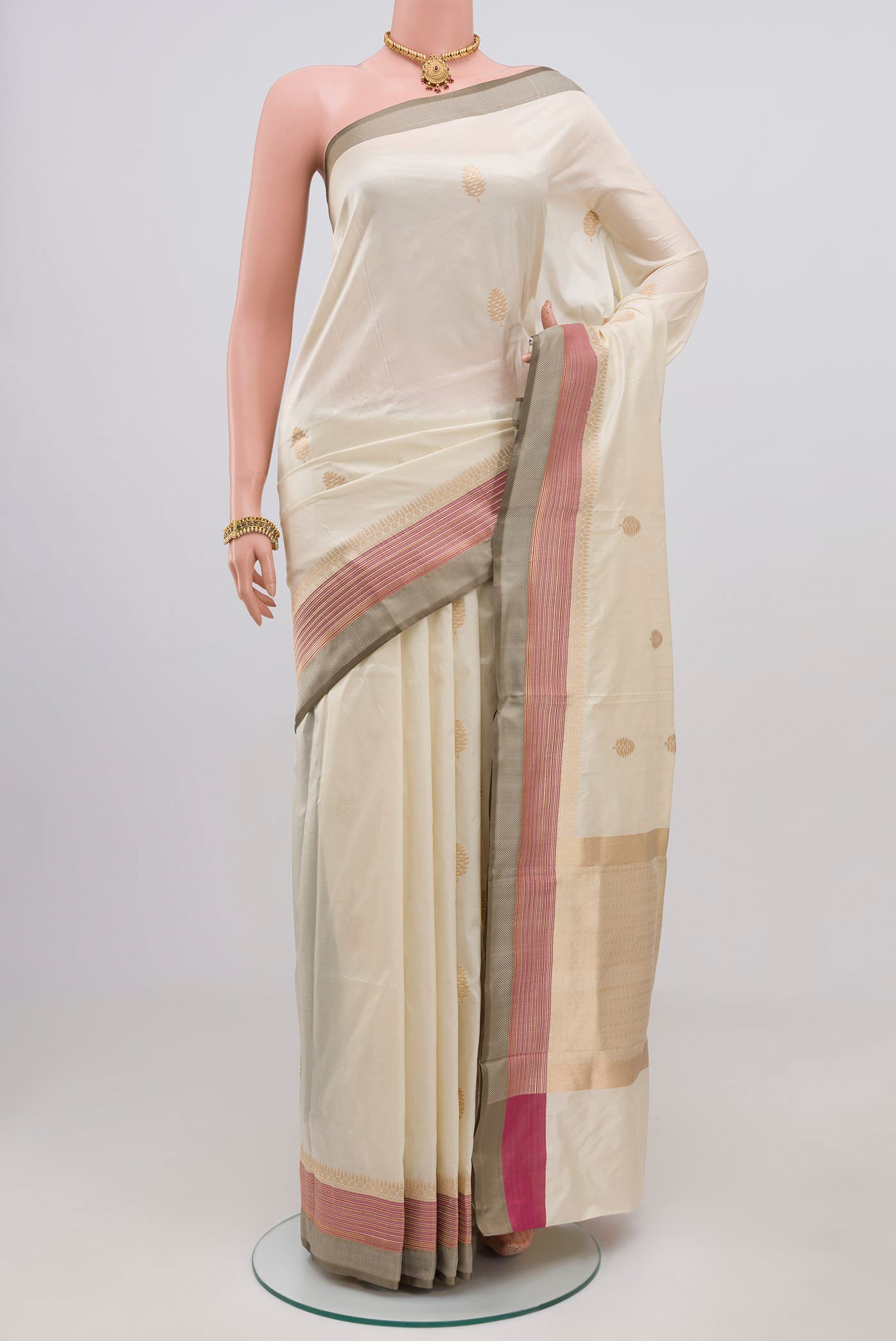 Cream Banarasi Katan Silk Saree with Zari Butta on the body and Thin Zari Line.  displayed on a mannequin