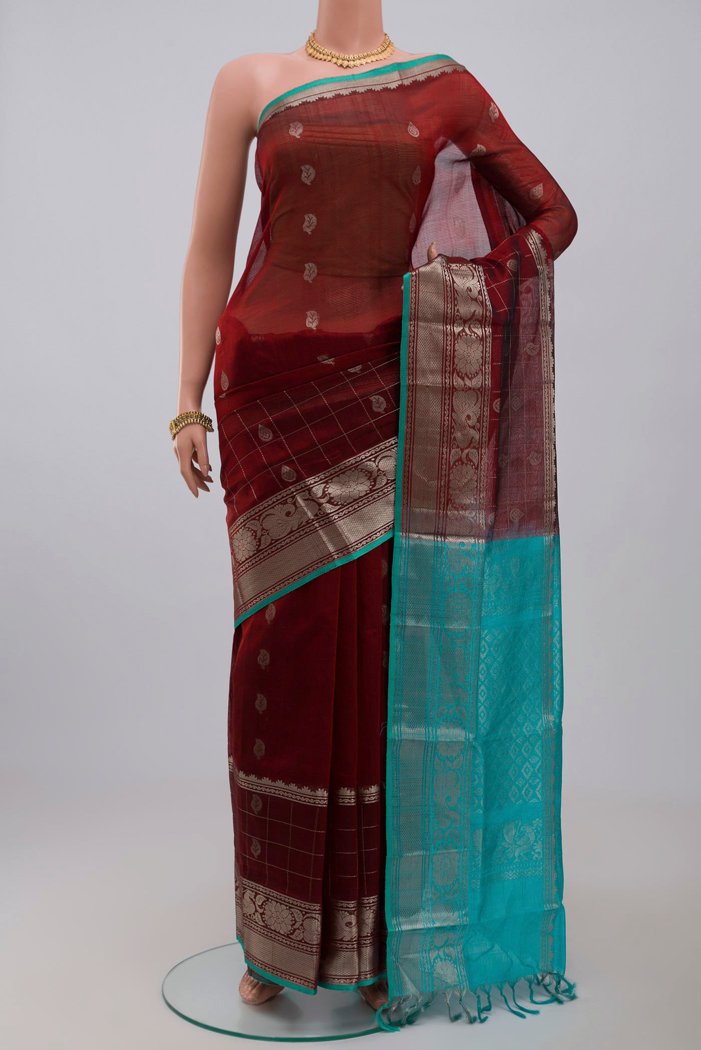 Maroon Silk Cotton Saree with Zari Butta on the body and Zari Border.  displayed on a mannequin