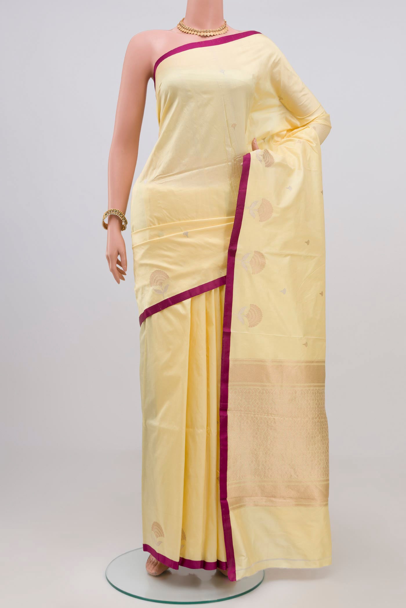 Yellow Banarasi Katan Silk Saree with Zari Butta on the body and Plain Border.  displayed on a mannequin