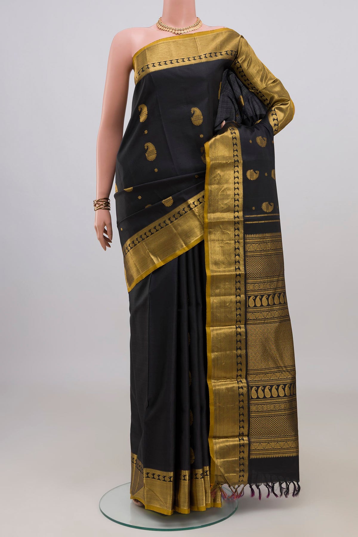 Pure Silk Black Kanjivaram Saree with Zari Butta on the body and Zari Border.  displayed on a mannequin