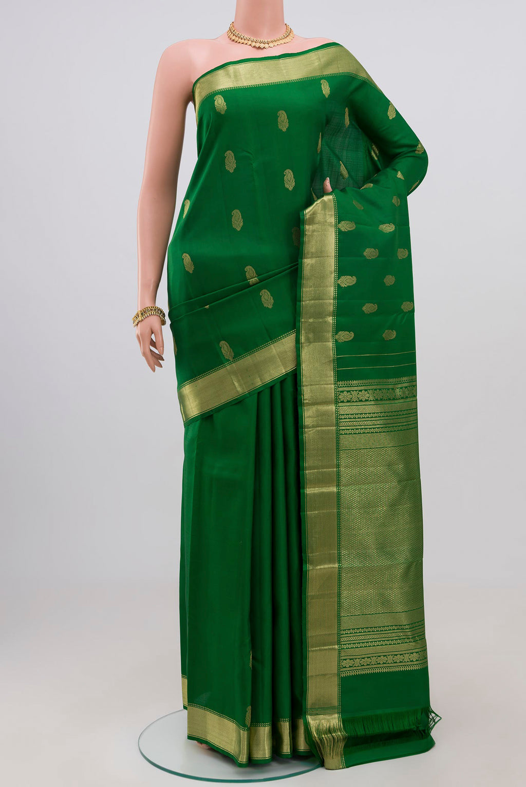 Green Kanchipuram Silk Saree with Zari Butta on the body and Zari Border.  displayed on a mannequin