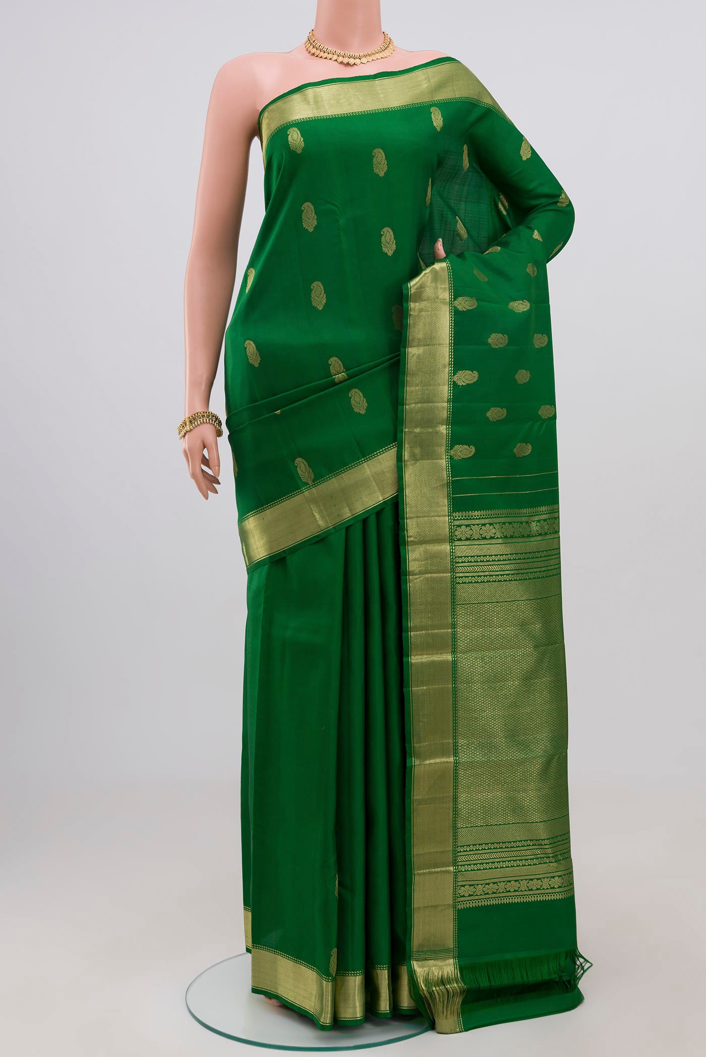 Green Kanchipuram Silk Saree with Zari Butta on the body and Zari Border.  displayed on a mannequin