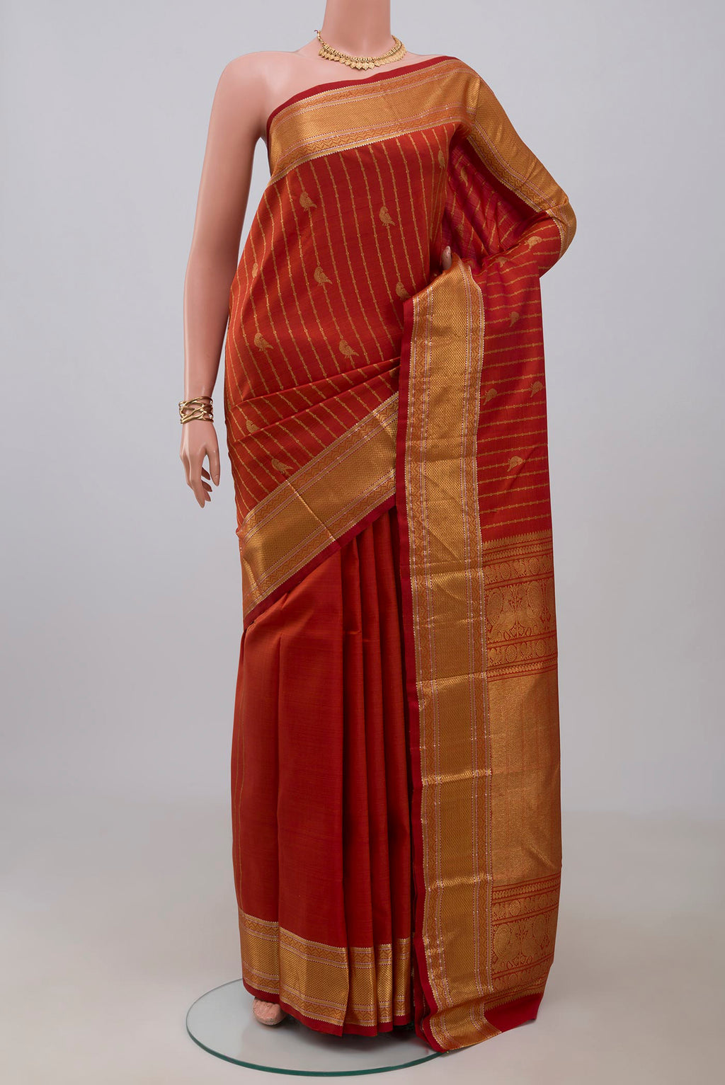 Rust Kanchipuram Silk Saree with Stripes on the body and Zari Border.  displayed on a mannequin