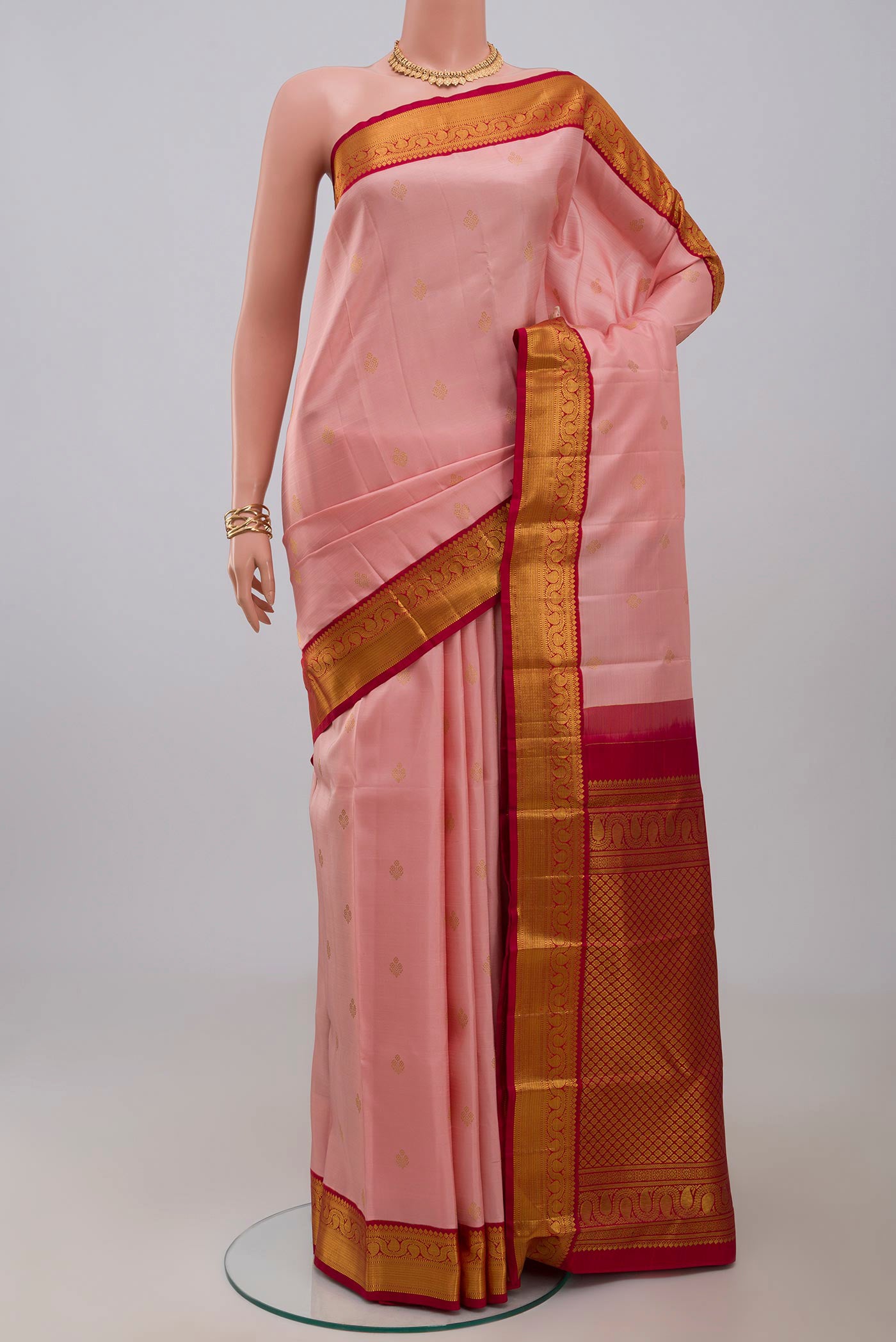 Peach Kanjivaram Silk Saree with Zari Butta on the body and Zari Border.  displayed on a mannequin