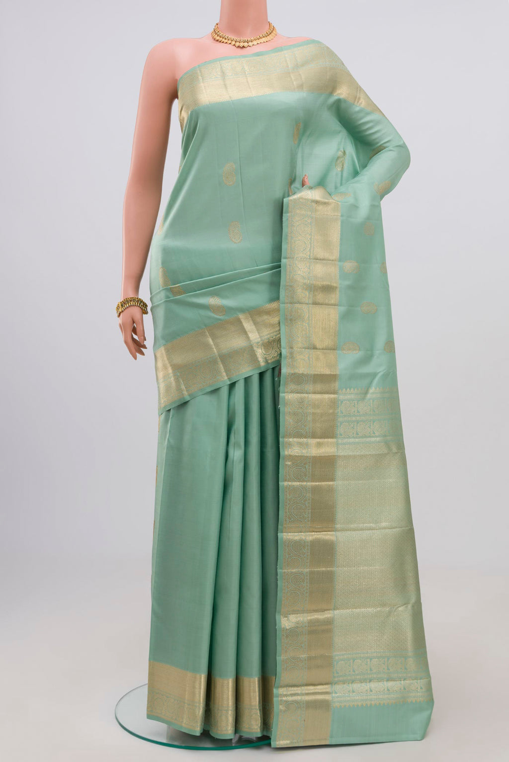 Green Kanjivaram Saree with Zari Butta on the body and Zari Border.  displayed on a mannequin