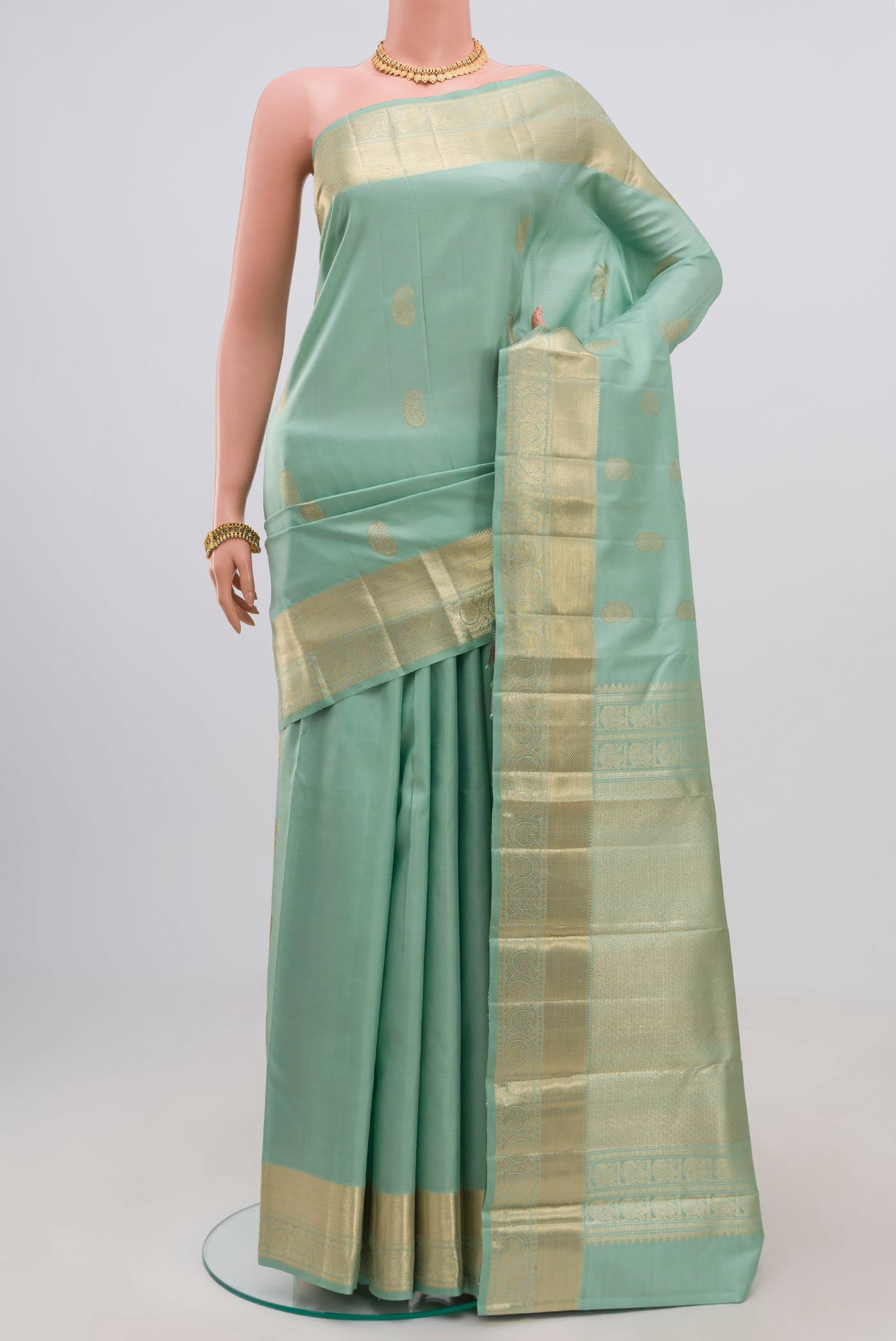 Green Kanjivaram Saree with Zari Butta on the body and Zari Border.  displayed on a mannequin