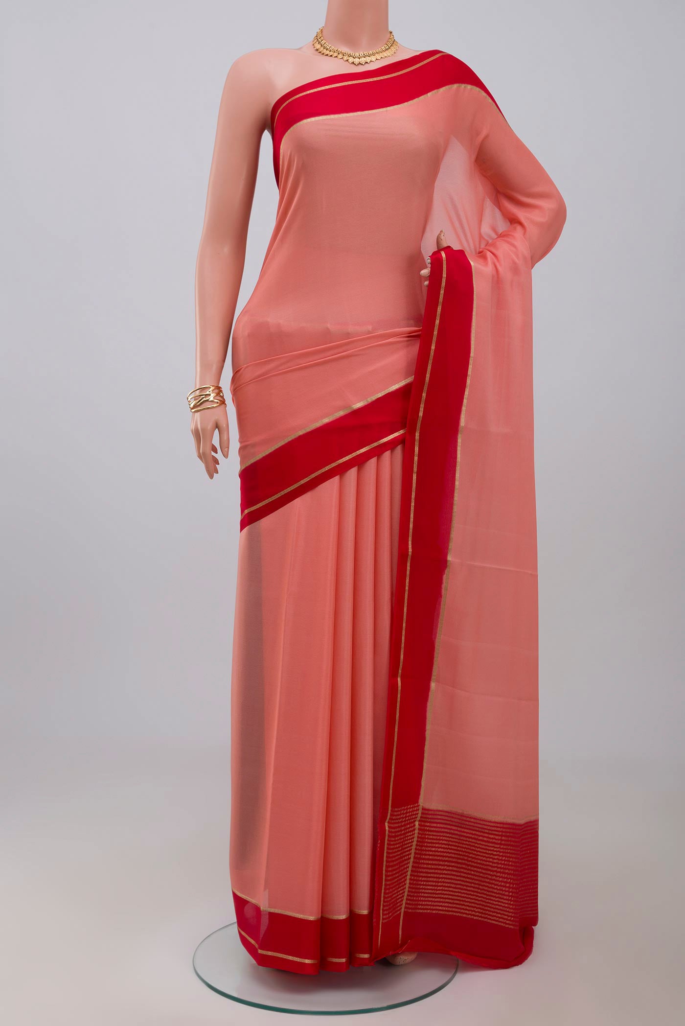 Peach Crepe Saree with Plain Body and Thin Zari Line.  displayed on a mannequin