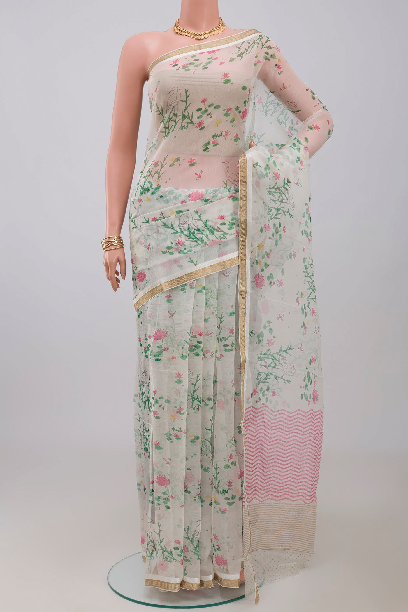 White Chiffon Saree with Printed design on the body and Zari Border.  displayed on a mannequin