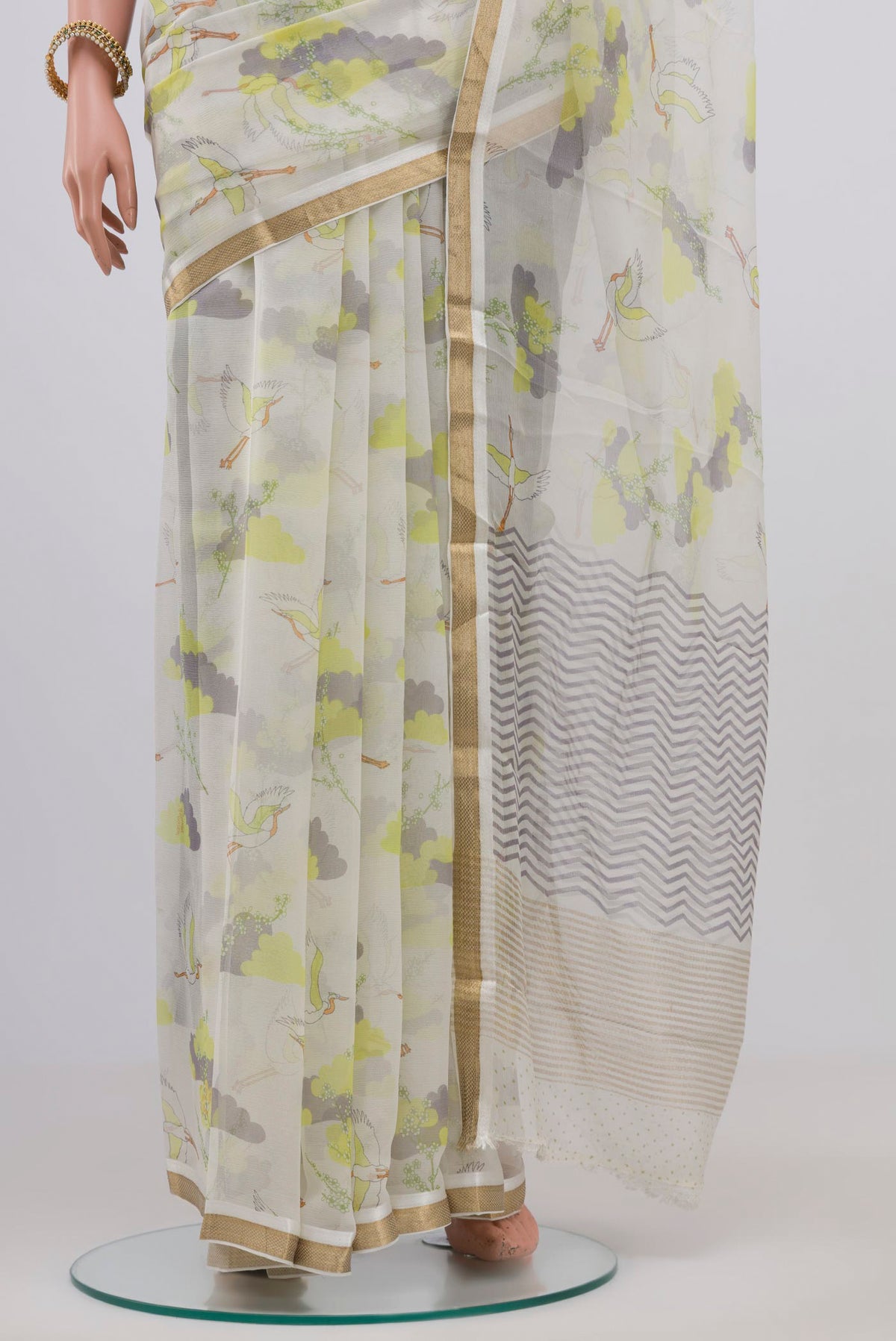 Pleats and pallu of Cream Chiffon Saree with Printed design on the body and Zari Border. 