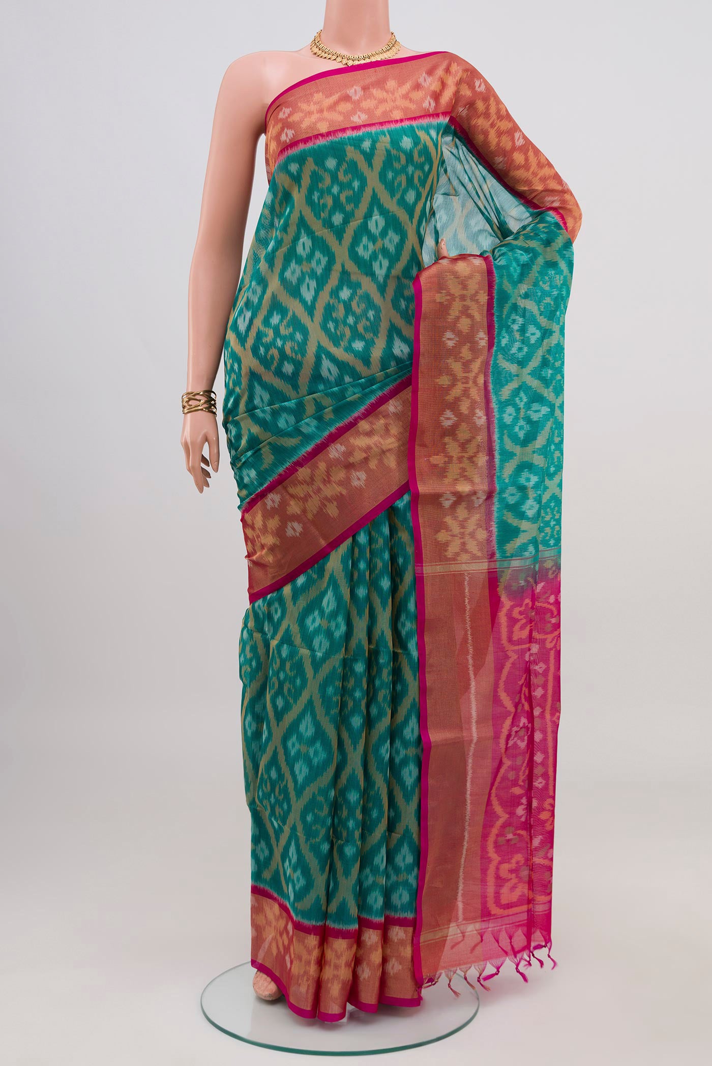 Turquoise Silk Cotton Saree with Ikat design on the body and Zari Border.  displayed on a mannequin