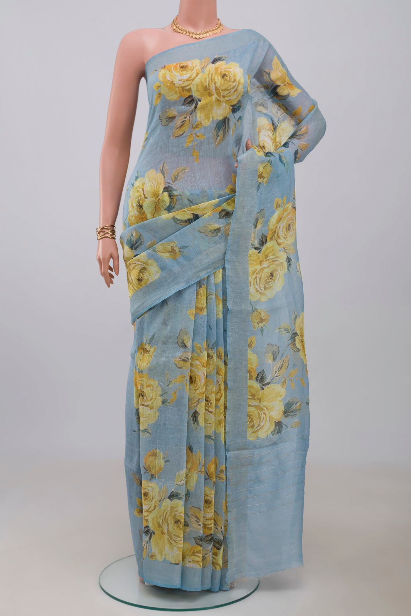 Sky Blue Linen Cotton Saree with Floral Print on the body and Thin Zari Line.  displayed on a mannequin