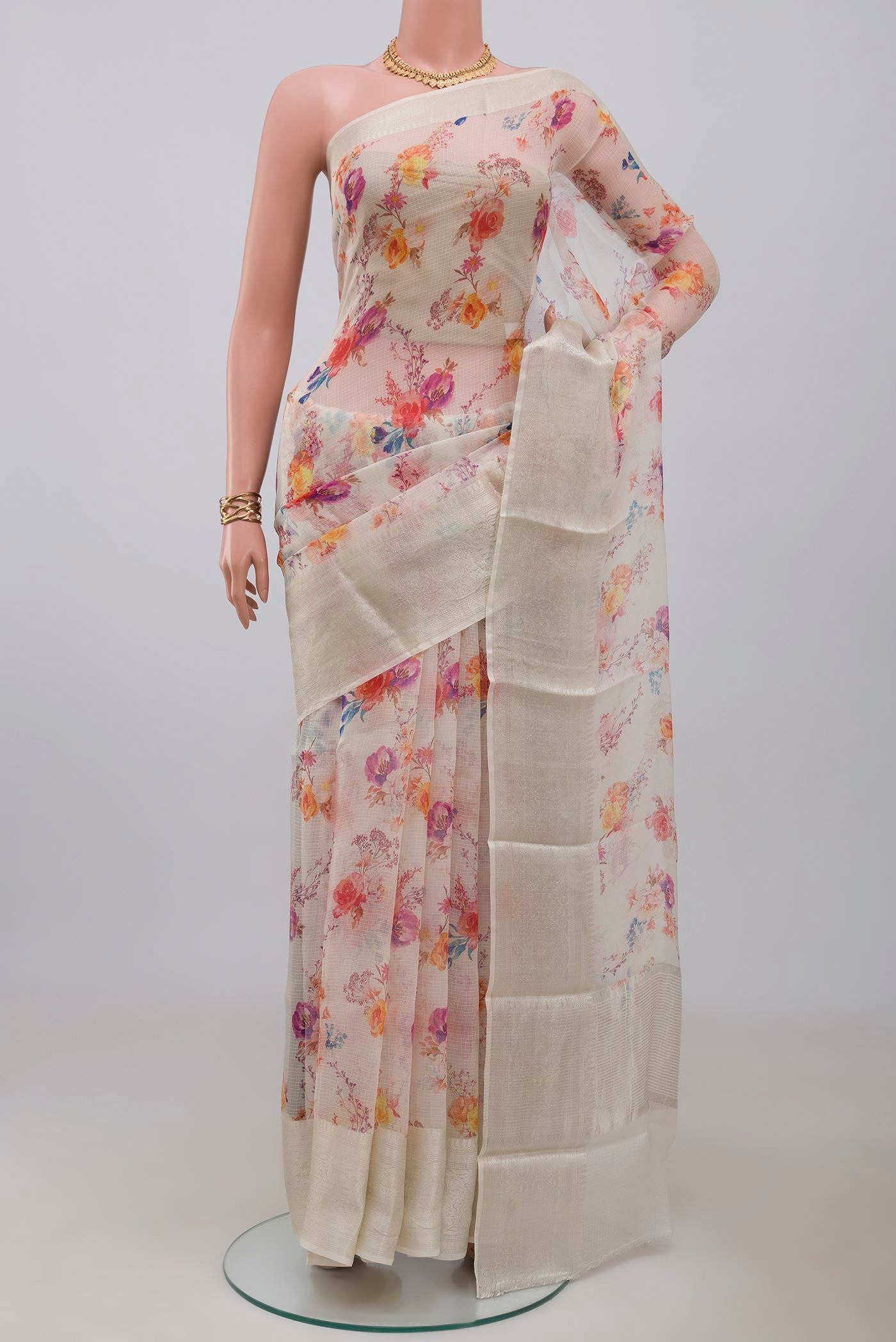 Cream Kota Silk Saree with Floral Print on the body and Zari Border.  displayed on a mannequin
