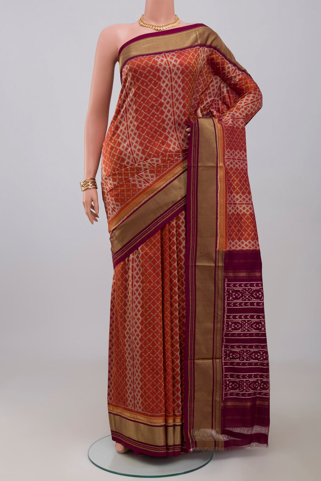 Rust Pochampally Silk Saree with Ikat design on the body and Zari Border.  displayed on a mannequin