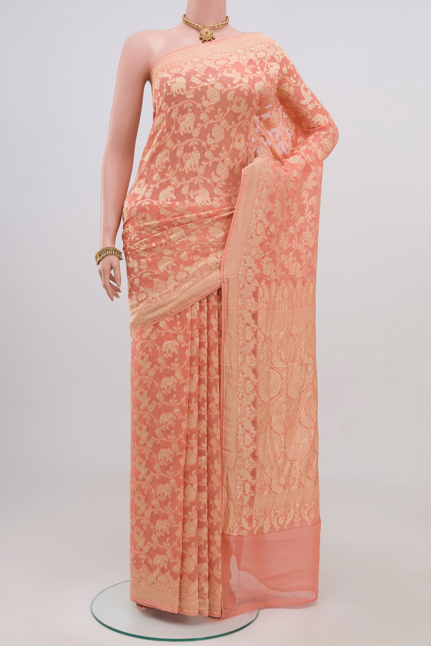 Peach Georgette Saree with Fancy on the body and Zari Border.  displayed on a mannequin