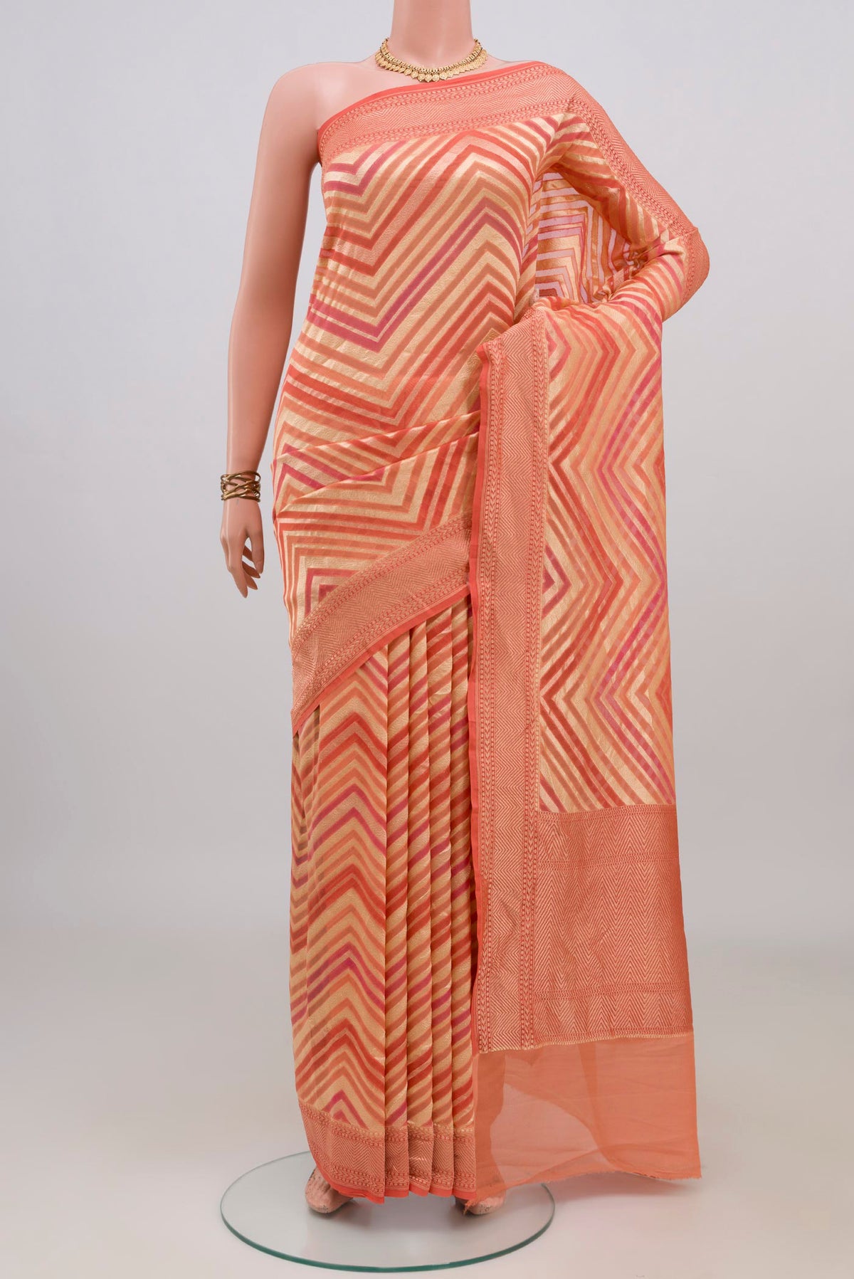 Peach Banarasi Georgette Saree with Zig Zag design on the body and Zari Border.  displayed on a mannequin