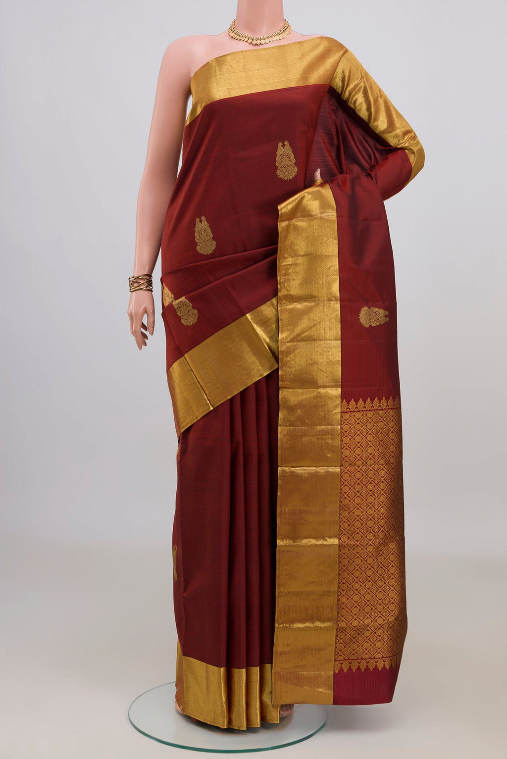 Pure Silk Maroon Kanchipuram Saree with Zari Butta on the body and Zari Border.  displayed on a mannequin