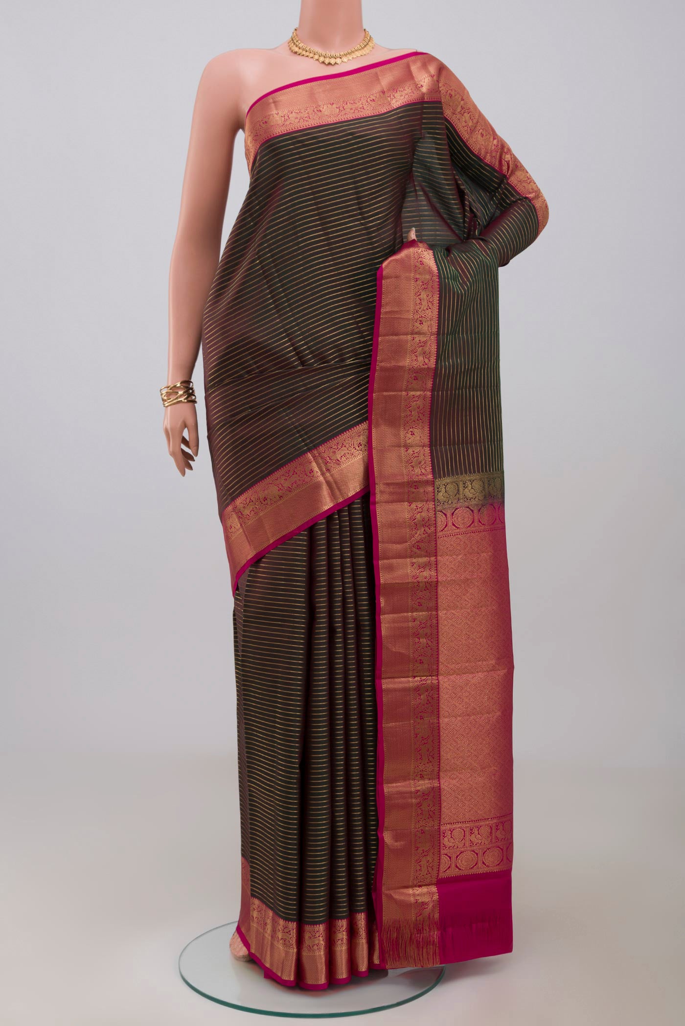 Green Kanjivaram Saree with Stripes on the body and Zari Border.  displayed on a mannequin