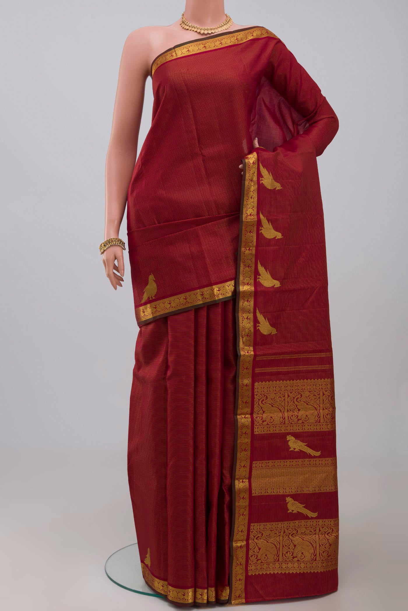 Maroon Kanchipuram Silk Saree with Stripes on the body and Zari Border.  displayed on a mannequin