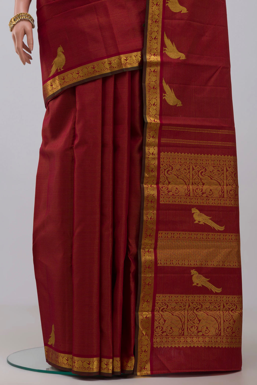 Pleats and pallu of Maroon Kanchipuram Silk Saree with Stripes on the body and Zari Border. 