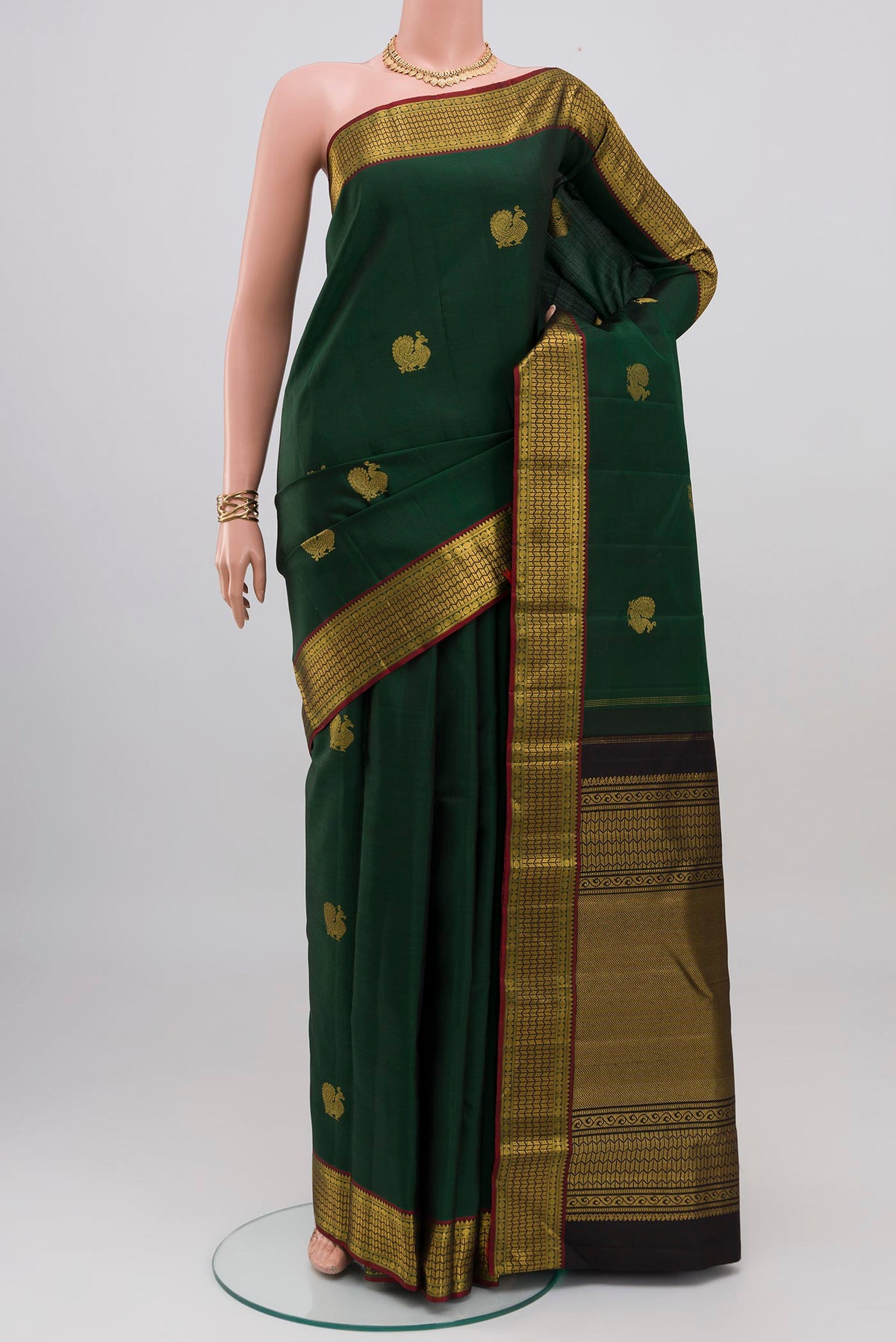 Bottle Green Kanjivaram Silk Saree with Zari Butta on the body and Zari Border.  displayed on a mannequin