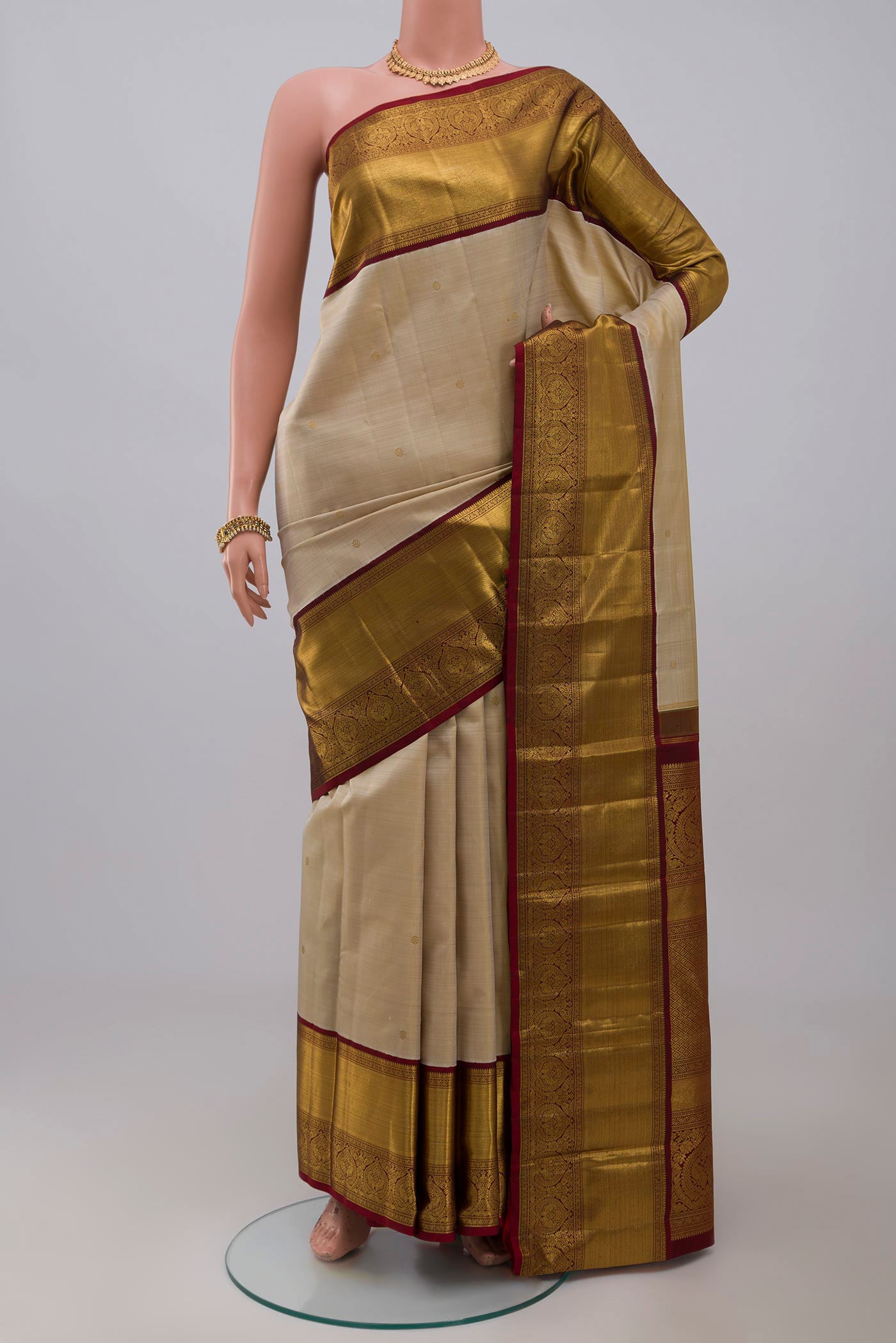 Pure Silk Pure Zari Off White Kanchipuram Saree with Zari Butta on the body and Zari Border.  displayed on a mannequin
