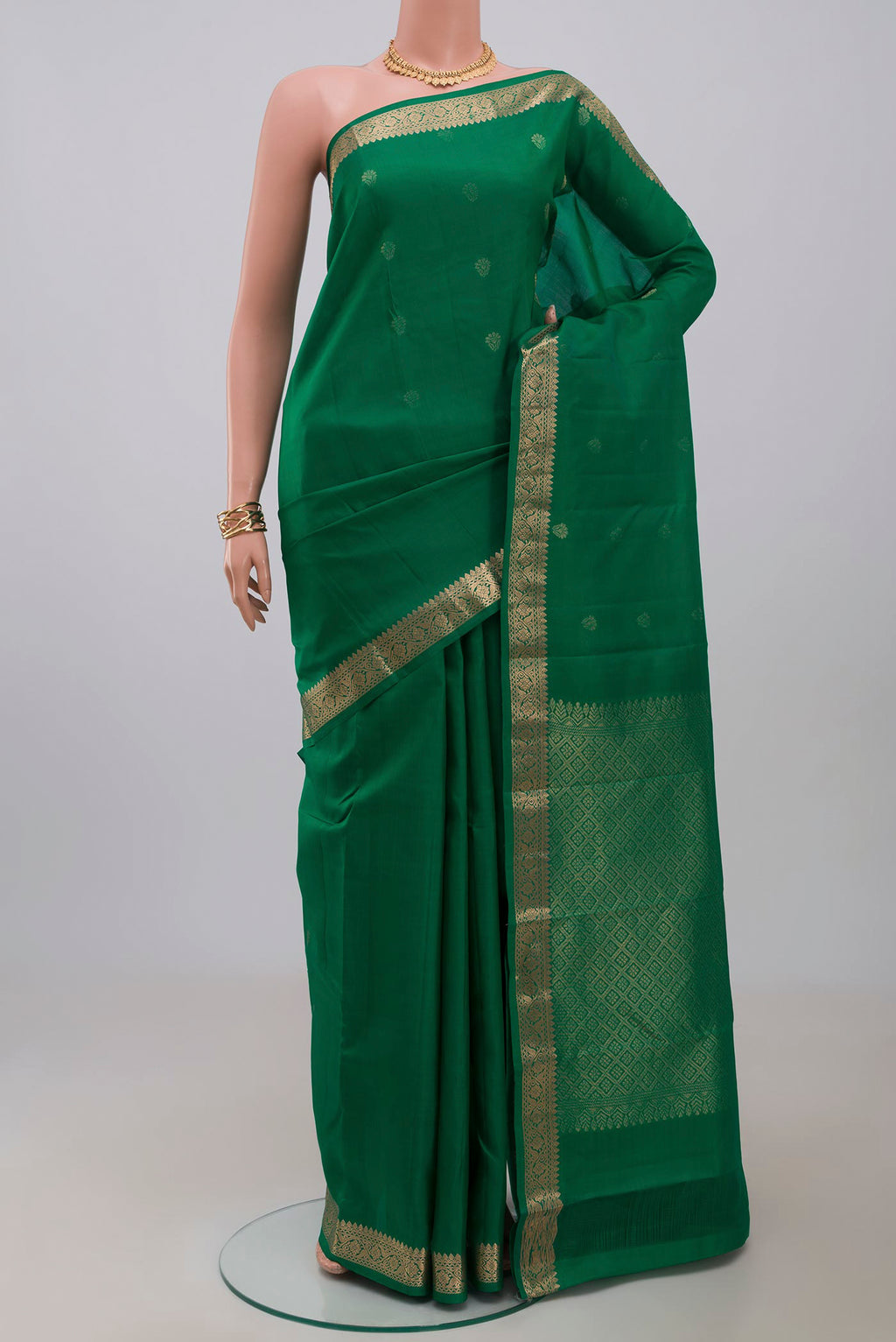 Green Kanjivaram Silk Saree with Zari Butta on the body and Zari Border.  displayed on a mannequin