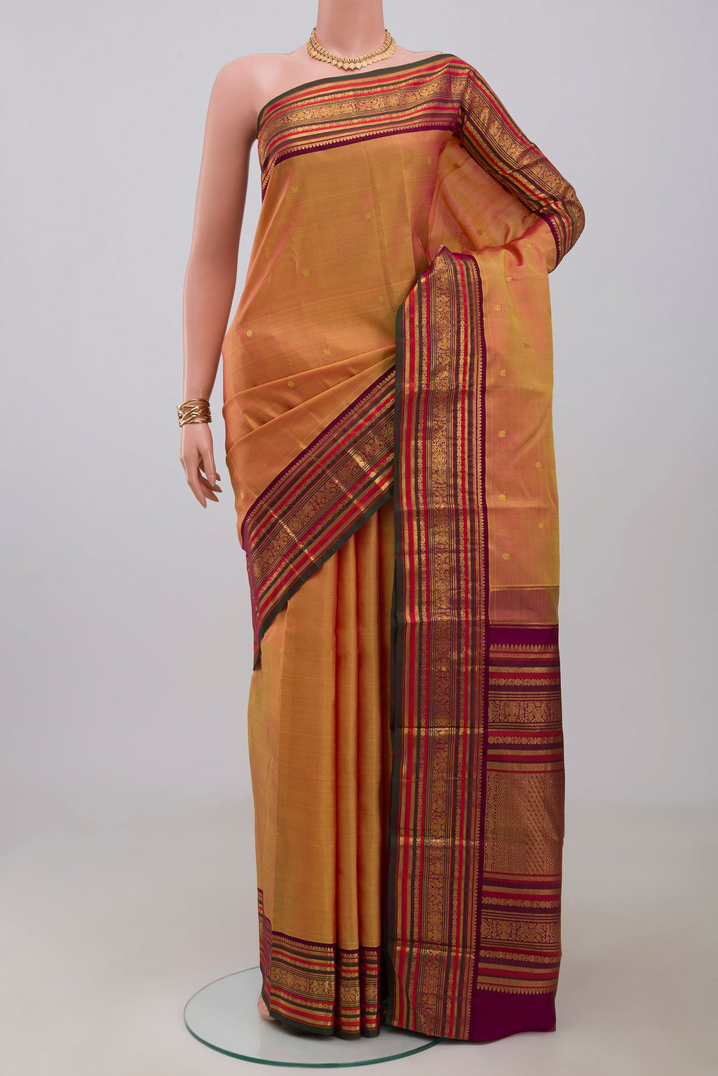 Mustard Kanjivaram Silk Saree with Zari Butta on the body and Zari Border.  displayed on a mannequin