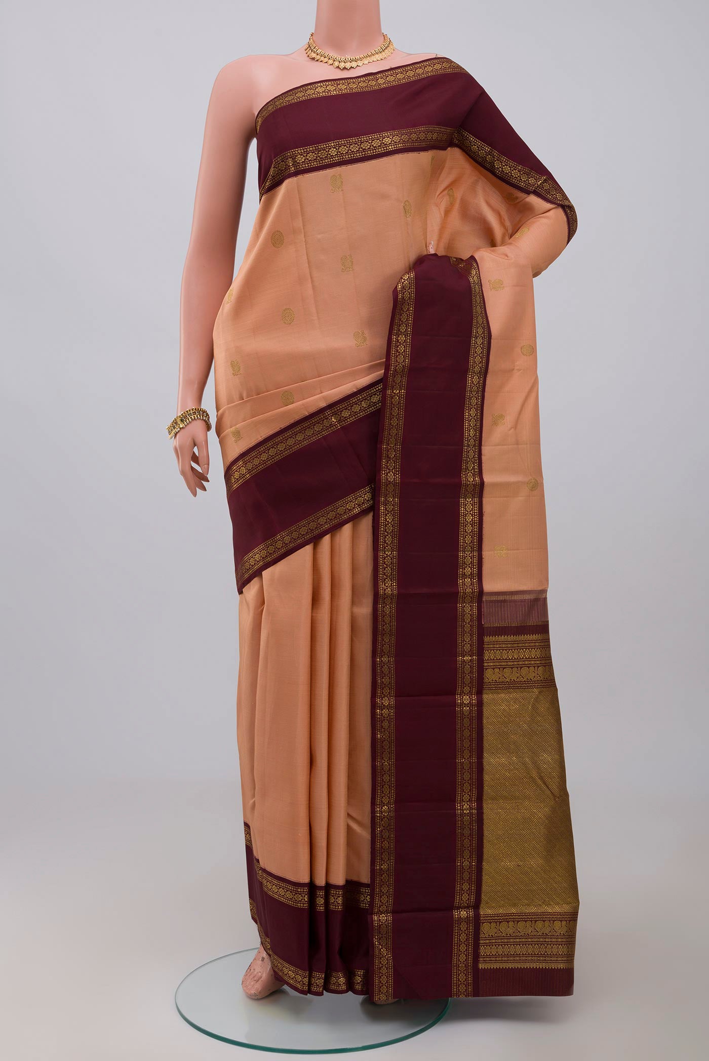 Pure Silk Pure Zari Peach Kanchipuram Saree with Zari Butta on the body and Zari Border.  displayed on a mannequin