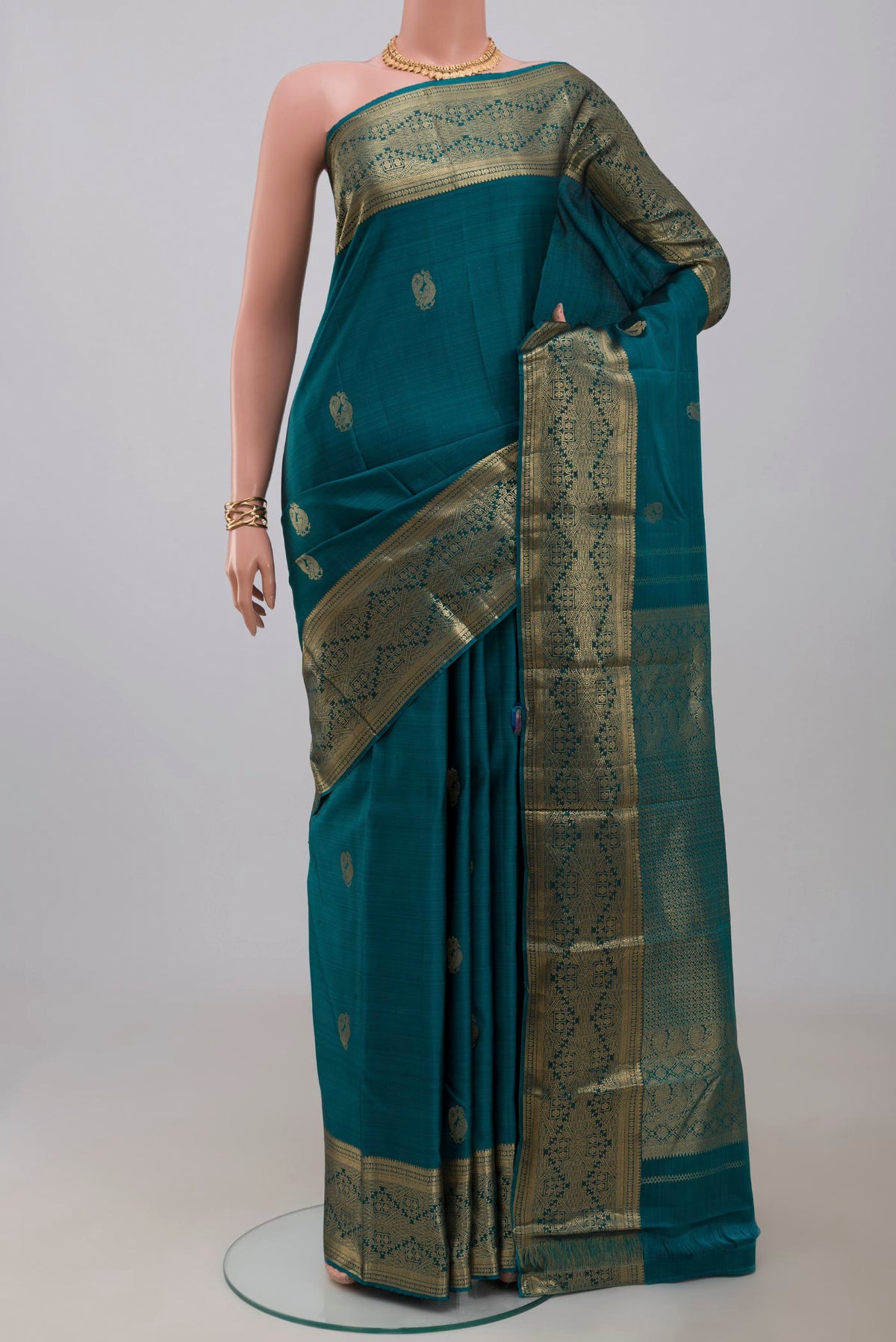 Teal Kanchipuram Silk Saree with Zari Butta on the body and Zari Border.  displayed on a mannequin