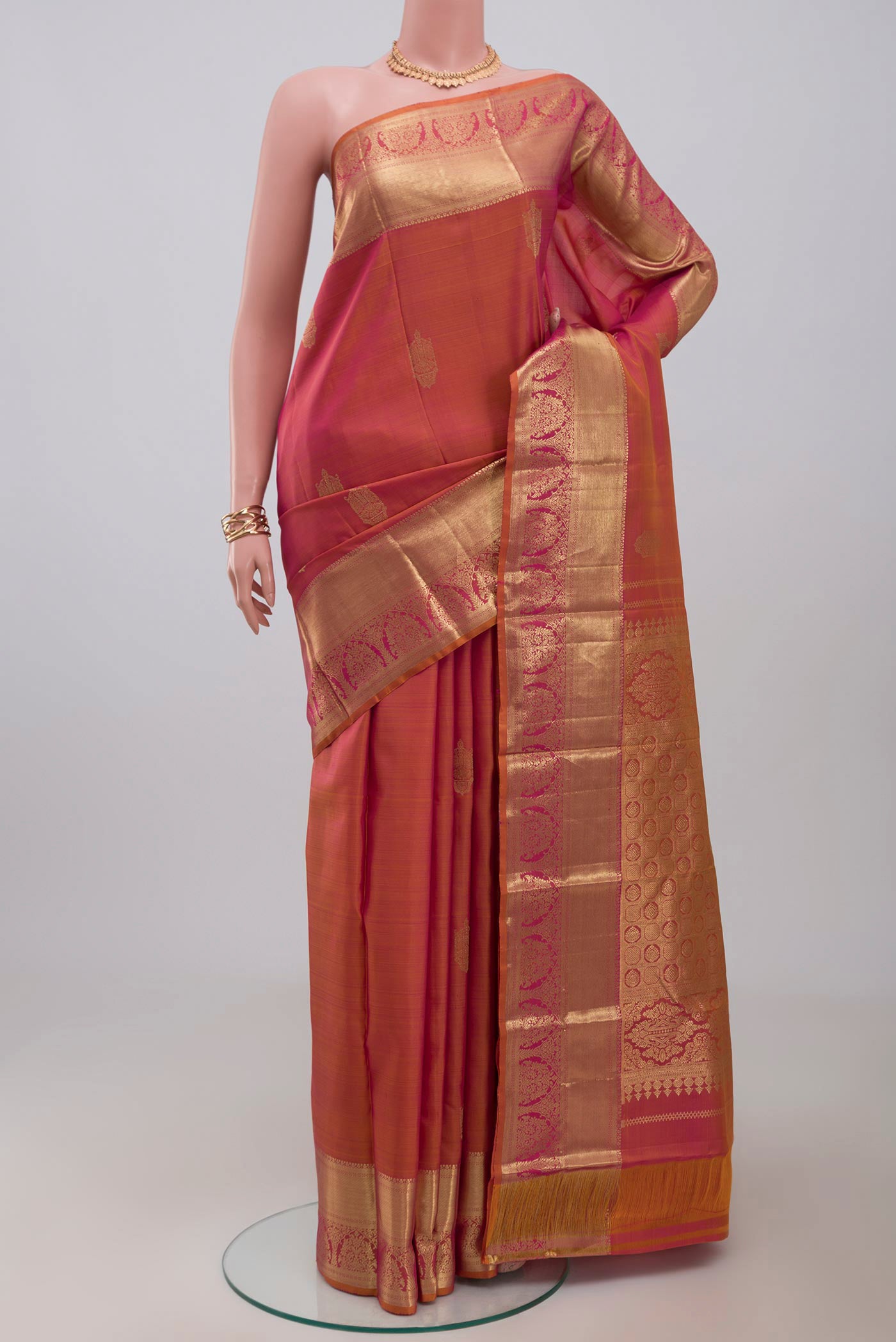 Orange Kanchipuram Silk Saree with Zari Butta on the body and Zari Border.  displayed on a mannequin