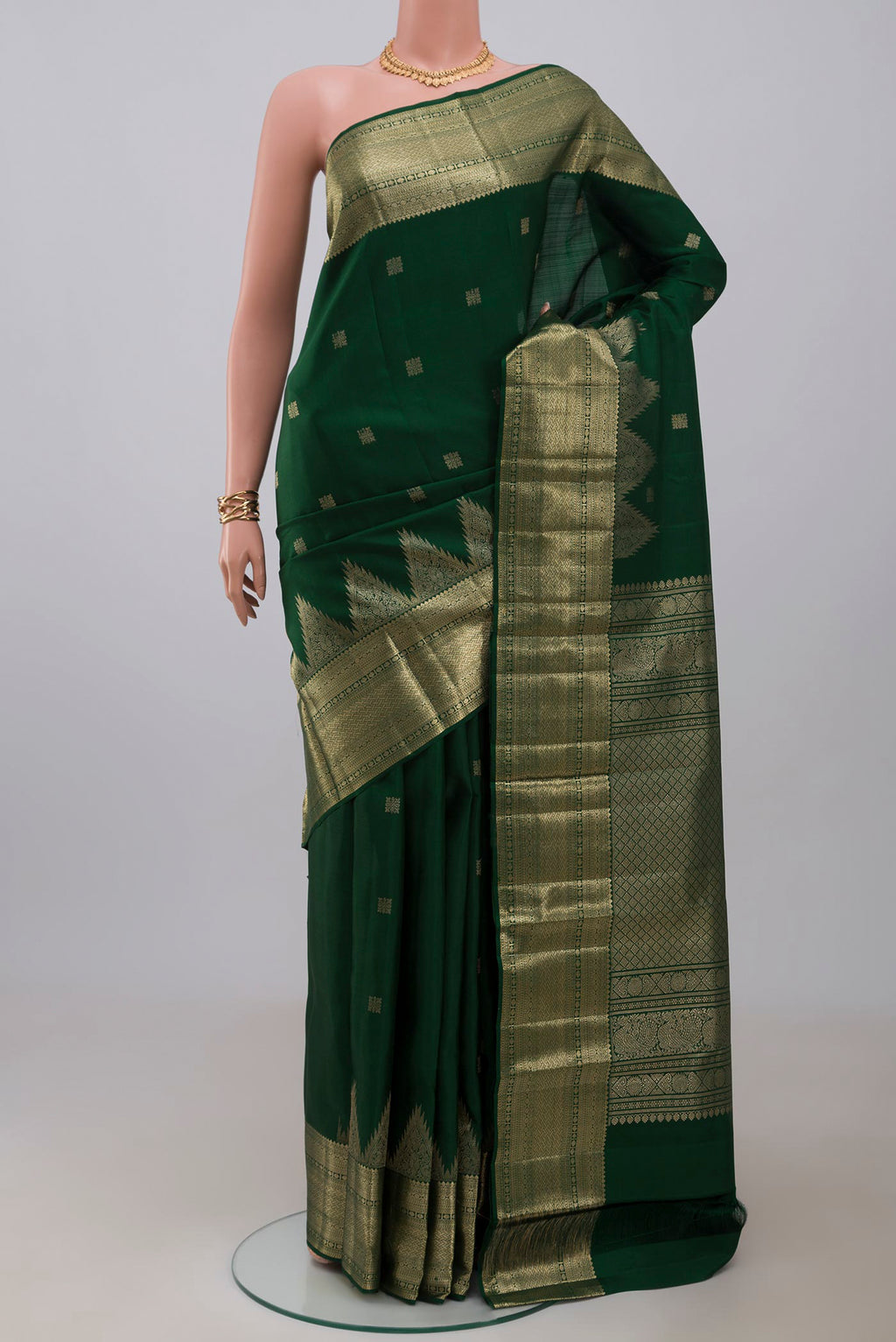 Bottle Green Kanjivaram Silk Saree with Zari Butta on the body and Temple Border.  displayed on a mannequin