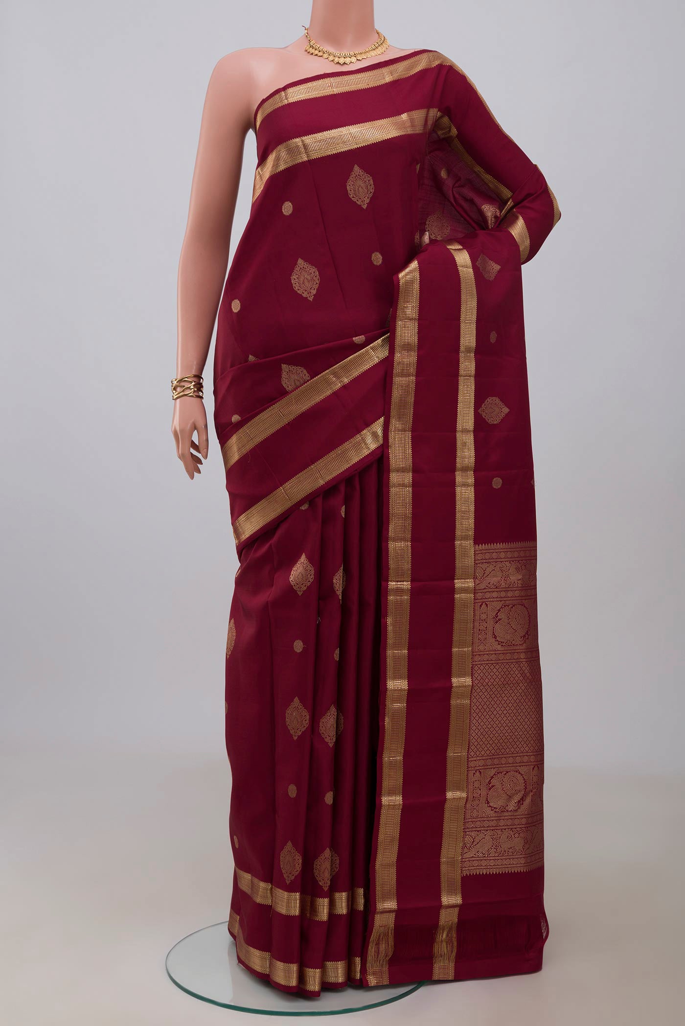 Maroon Kanjivaram Silk Saree with Zari Butta on the body and Zari Border.  displayed on a mannequin