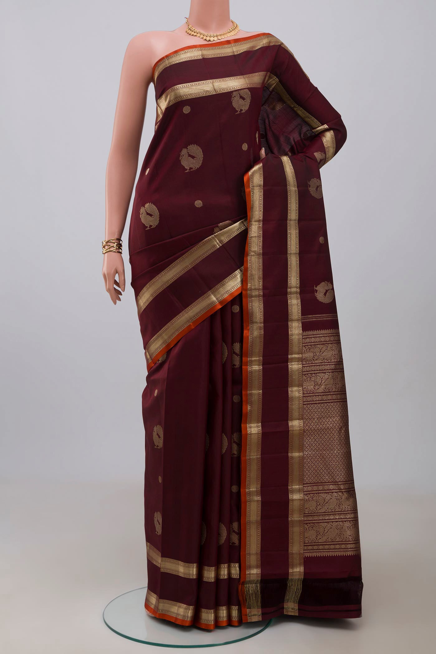 Maroon Kanjivaram Silk Saree with Zari Butta on the body and Zari Border.  displayed on a mannequin