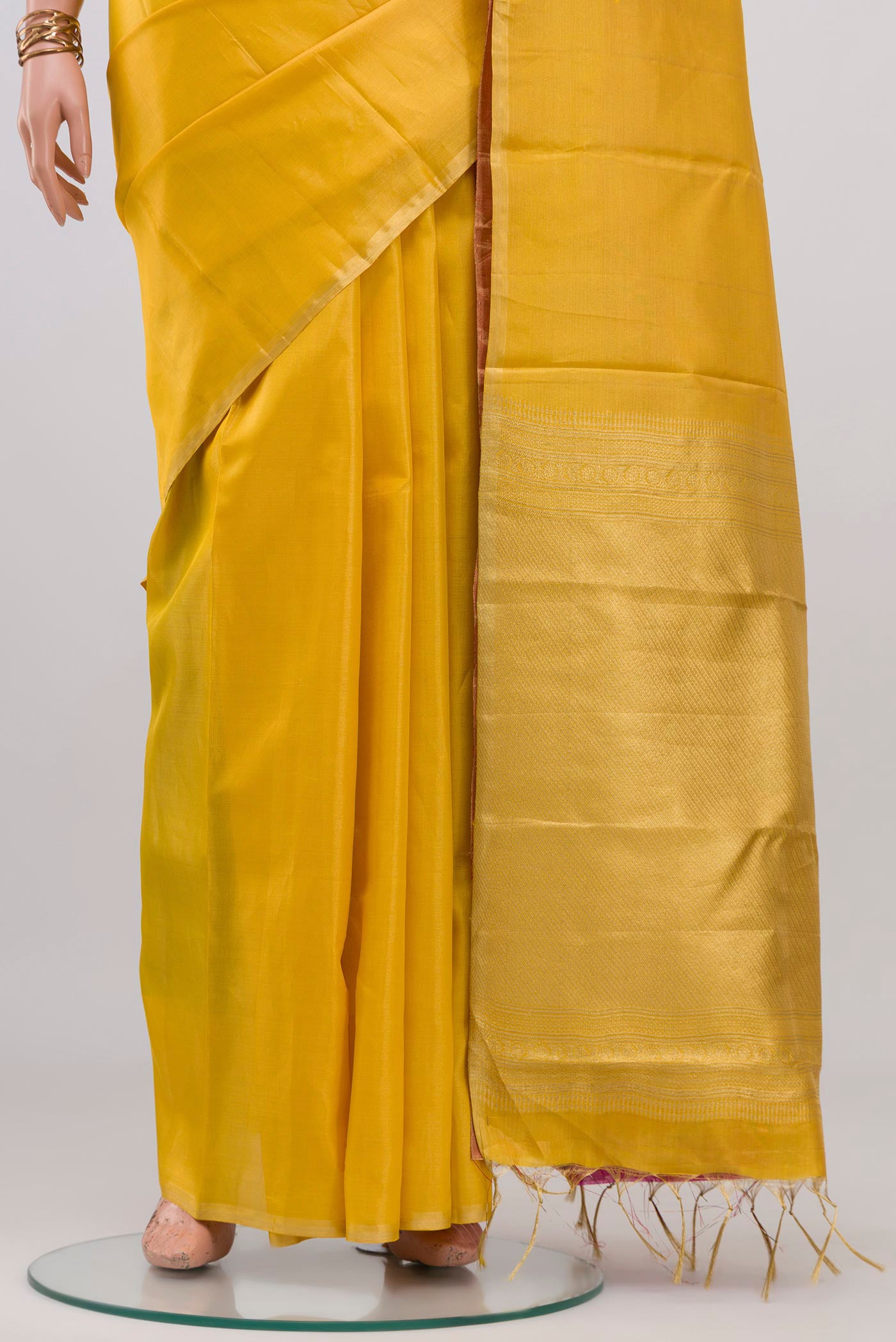 Pleats and pallu of Yellow Soft Silk Saree with Plain Body and Zari Border. 