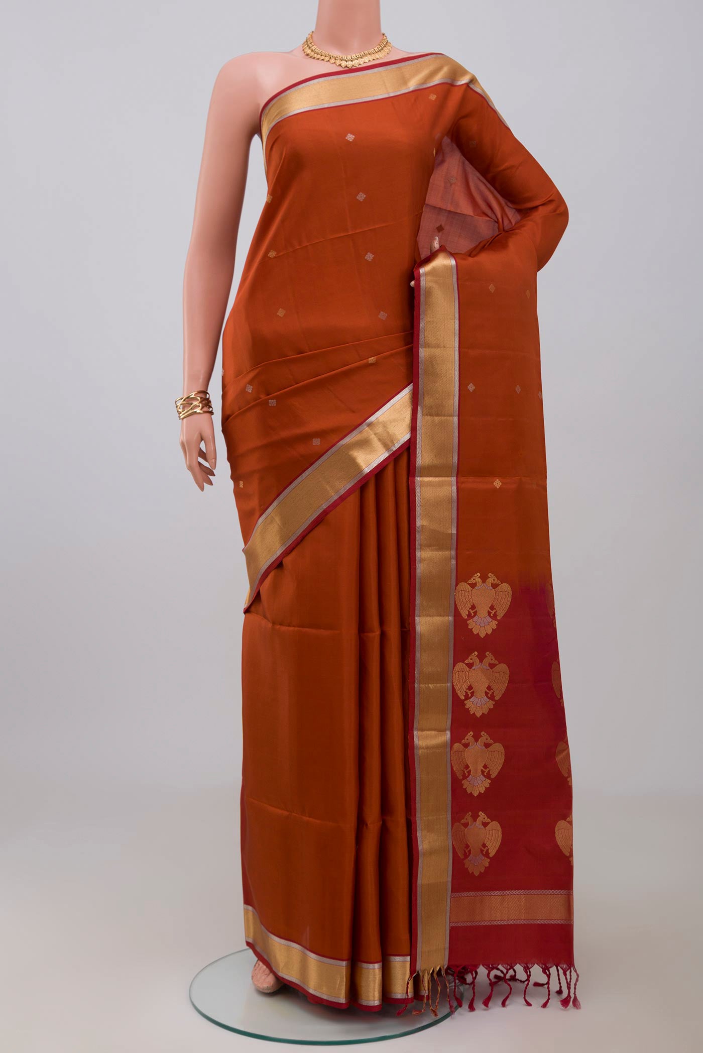 Rust Soft Silk Saree with Zari Butta on the body and Zari Border.  displayed on a mannequin