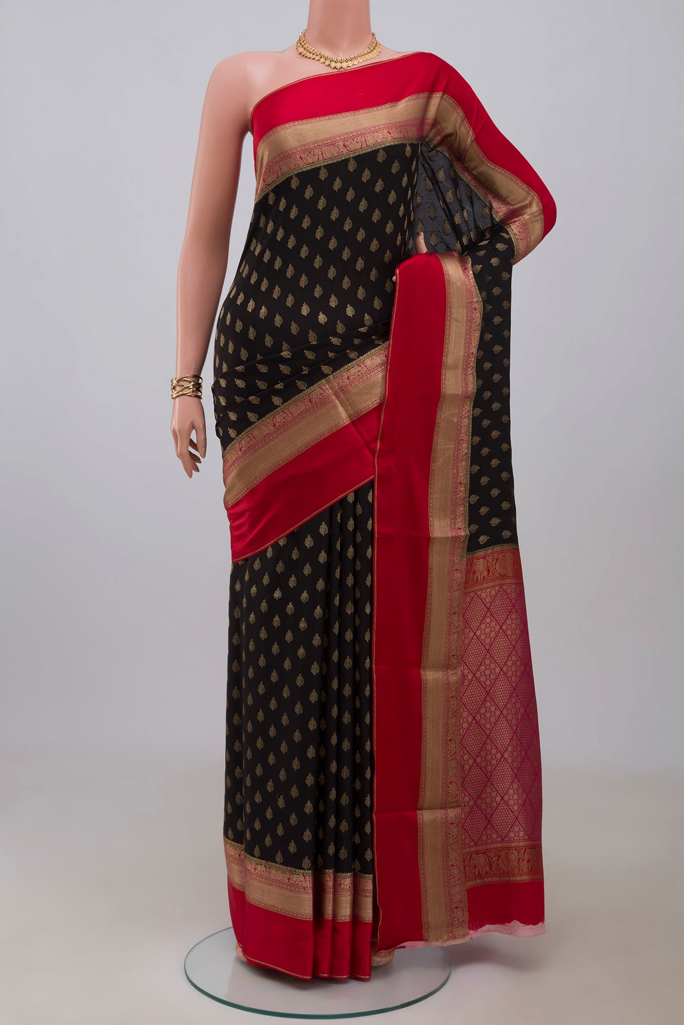 Black Crepe Saree with Zari Butta on the body and Zari Border.  displayed on a mannequin