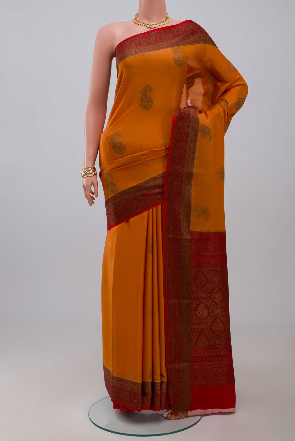 Orange Crepe Saree with Zari Butta on the body and Zari Border.  displayed on a mannequin