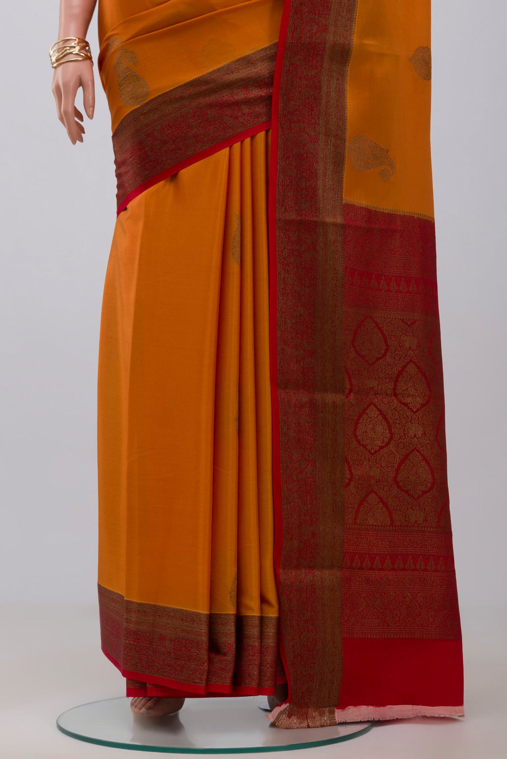Pleats and pallu of Orange Crepe Saree with Zari Butta on the body and Zari Border. 